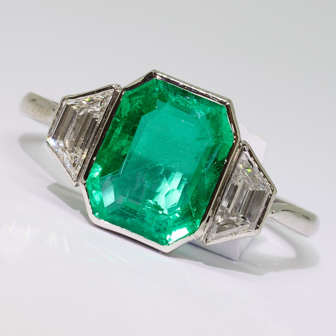 CERTIFICATED COLOMBIAN EMERALD AND DIAMOND 3-STONE RING: CERTIFICATED COLOMBIAN EMERALD AND DIAMOND 3-STONE RING,3,2 grams, testing platinum.Rich and vibrant emerald of approx. 2.37 ct. (Certificated, Colombian, Minor).Diamonds bright and lively.Size N