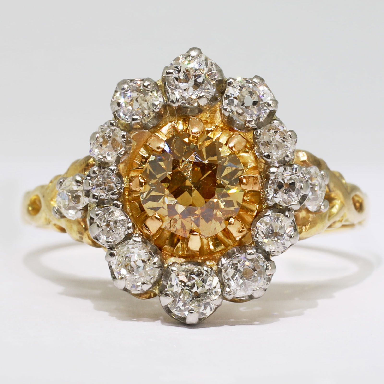 CERTIFICATED FANCY DEEP BROWNISH YELLOW DIAMOND AND WHITE DIAMOND CLUSTER RING: CERTIFICATED FANCY DEEP BROWNISH YELLOW DIAMOND AND WHITE DIAMOND CLUSTER RING,6.4 grams, 18 ct. gold and platinum, French marked.Fancy coloured diamond of approx. 1.05 ct.Surrounded by white