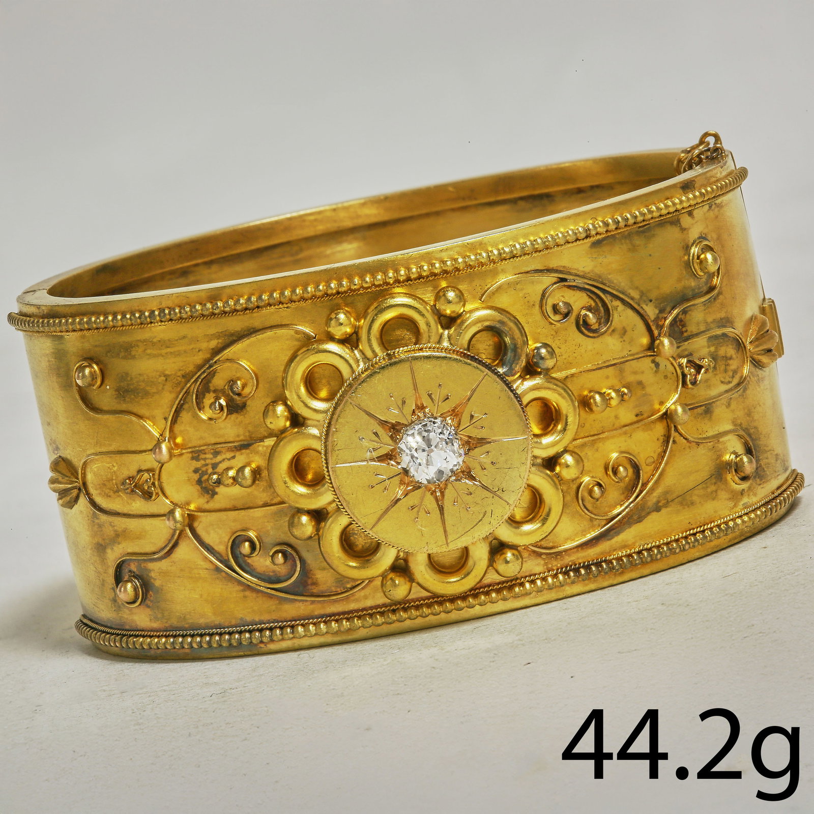 VICTORIAN ETRUSCAN REVIVAL DIAMOND CUFF BANGLE: VICTORIAN ETRUSCAN REVIVAL DIAMOND CUFF BANGLE,44,2 grams, testing high carat gold.The Bangle with lovely relief and applique decoration.Set with a bright and lively old cut diamond to the