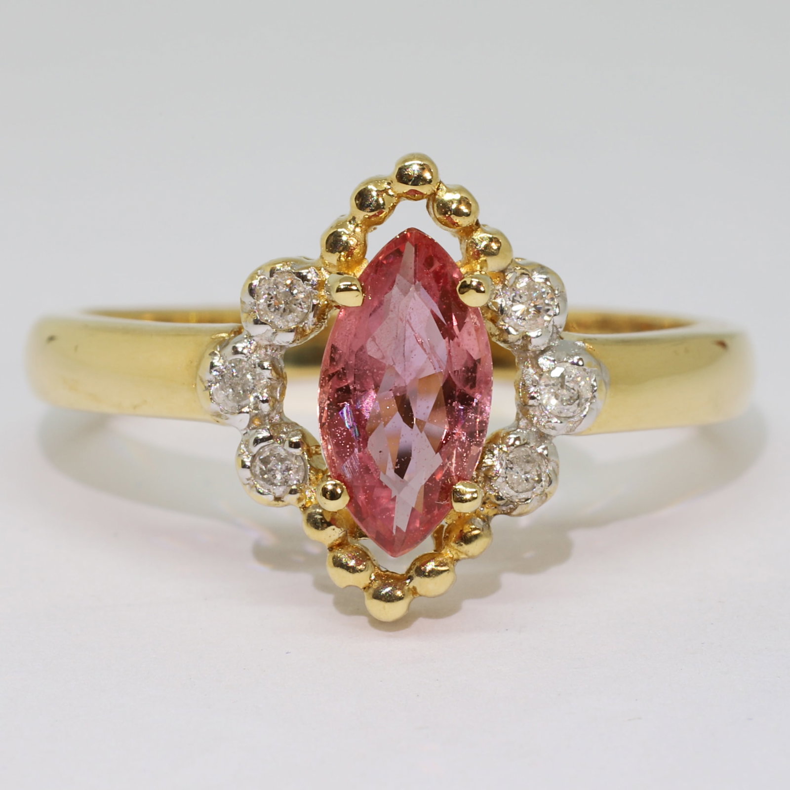 UNUSUAL PADPARADSCHA SAPPHIRE AND DIAMOND CLUSTER RING: UNUSUAL PADPARADSCHA SAPPHIRE AND DIAMOND CLUSTER RING,3,4 grams, 18 ct. gold.Lovely navette cut padparadscha sapphire, of approx. 8.90 mm.Diamonds bright and lively.Size N.