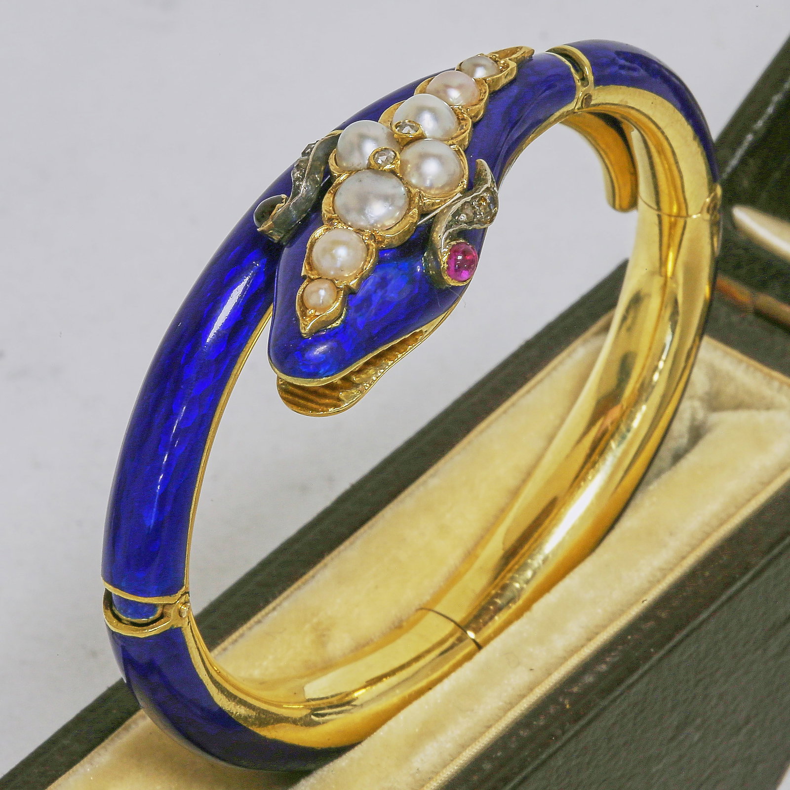 FANTASTIC ENAMEL AND PEARL SNAKE BANGLE: FANTASTIC ENAMEL AND PEARL SNAKE BANGLE,38.5 grams, testing high cart gold.The fine sculptured snakes head and body with blue enamel (in good condition. The snakes head further set with Pearls, diamon