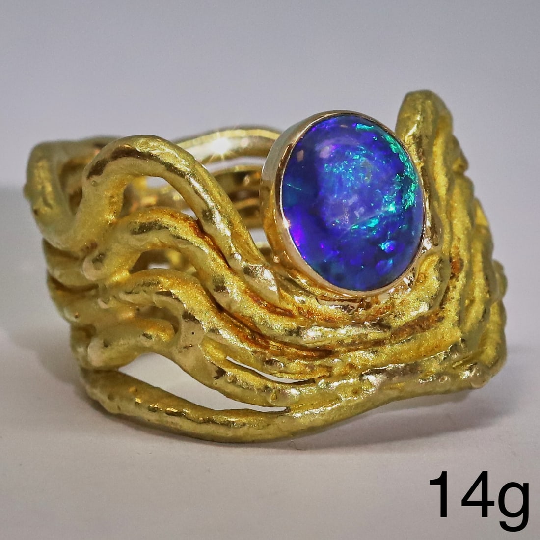 ANDREW GRIMA, MODERNIST BLACK OPAL RING: ANDREW GRIMA, MODERNIST BLACK OPAL RING,14 grams, 18 ct. gold.The ring of 5-band wave design, set with a black opal with great play of colour.Signed Grima and makers mark.Size O 1/2