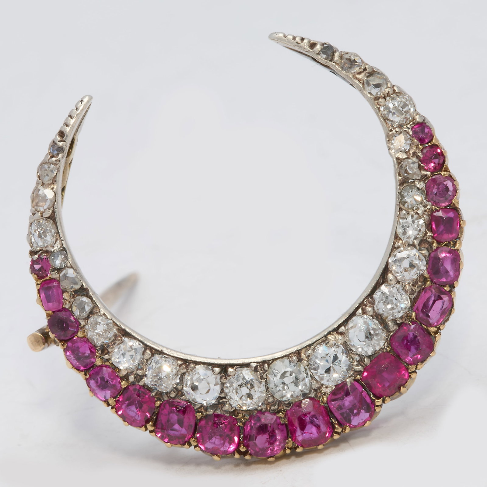 ANTIQUE RUBY AND DIAMOND CRESCENT BROOCH: ANTIQUE RUBY AND DIAMOND CRESCENT BROOCH,4 grams, testing high carat gold.Rich and vibrant rubies.Diamonds bright and lively.W. 2.5 cm.