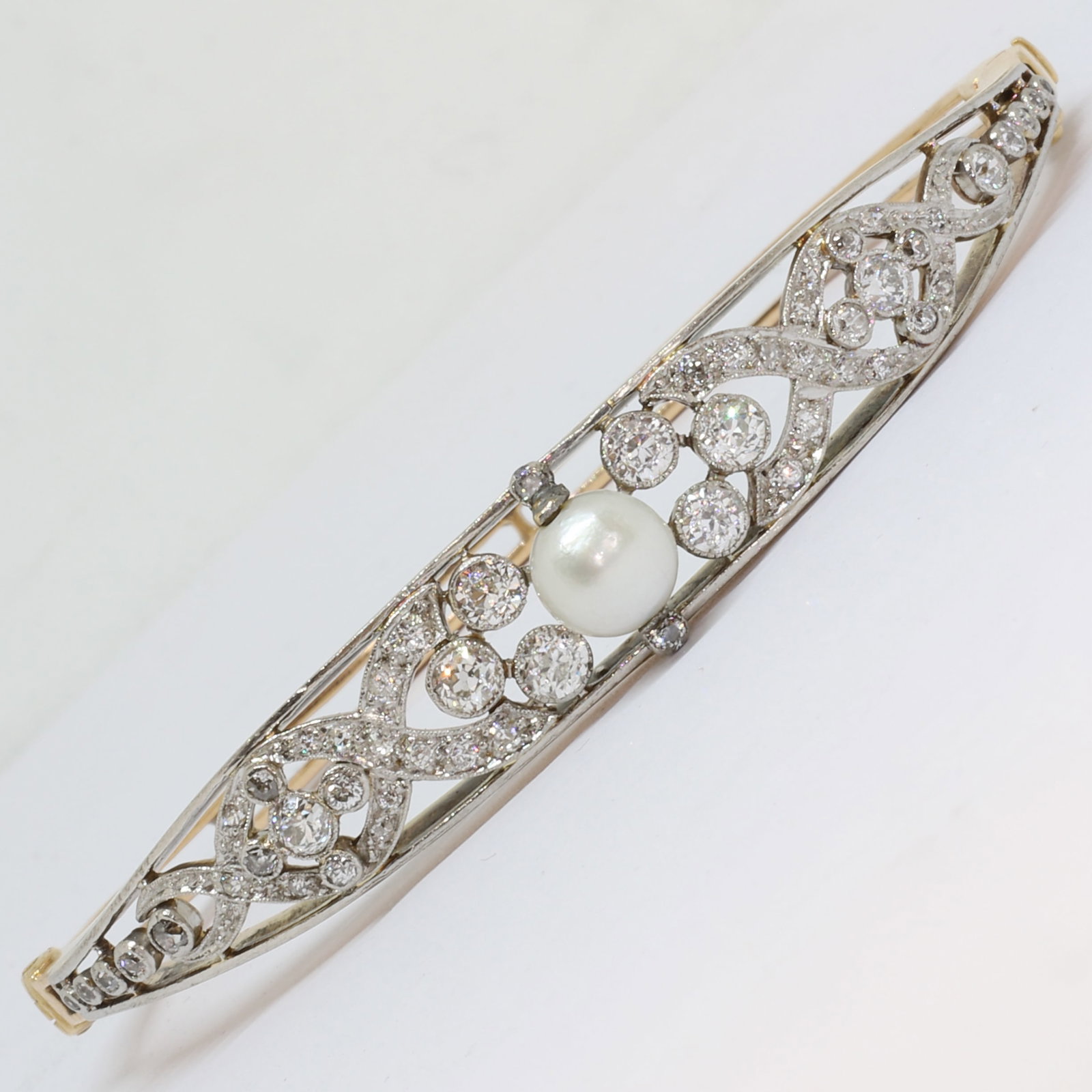PEARL AND DIAMOND HINGED BANGLE: PEARL AND DIAMOND HINGED BANGLE,18.8 grams, testing high carat gold.Diamonds bright and lively, totalling approx. 1.50 ct.Pearl of approx. 7.2 mm. (untested).Inner diam. 6.4 cm.