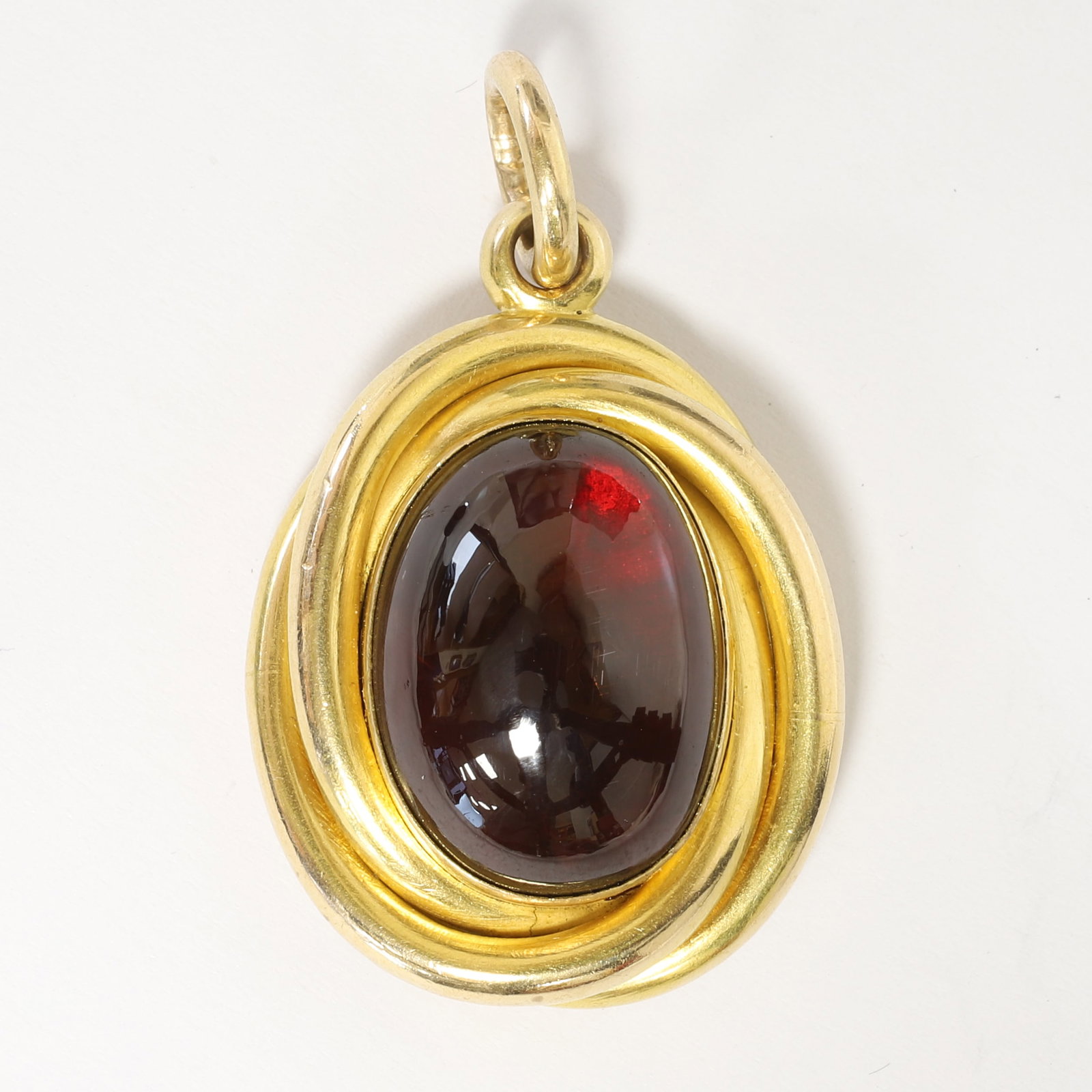 VICTORIAN GARNET LOCKET PENDANT: VICTORIAN GARNET LOCKET PENDANT,10.6 grams, testing 15 ct. gold.Lovely cabochon cut garnet.The surmount of entwined design.Locket back.L. 3.6 cm.