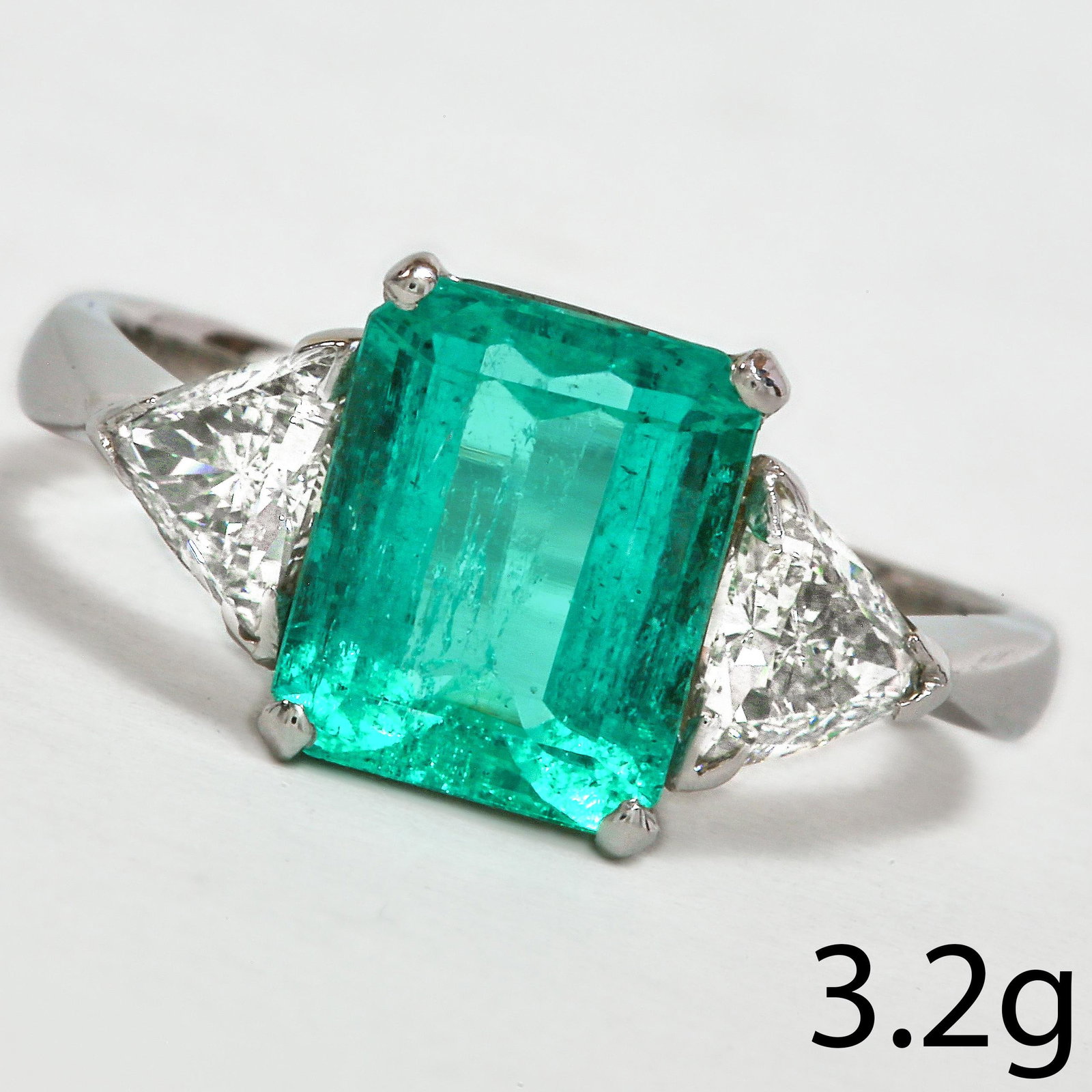EMERALD AND DIAMOND 3-STONE RING: EMERALD AND DIAMOND 3-STONE RING,3.2 grams, 18 ct. gold. Fully British hallmarked.Rich and vibrant emerald of approx. 1.90 ct.Diamonds bright and lively, totalling approx. 0.80 ct.Size L.