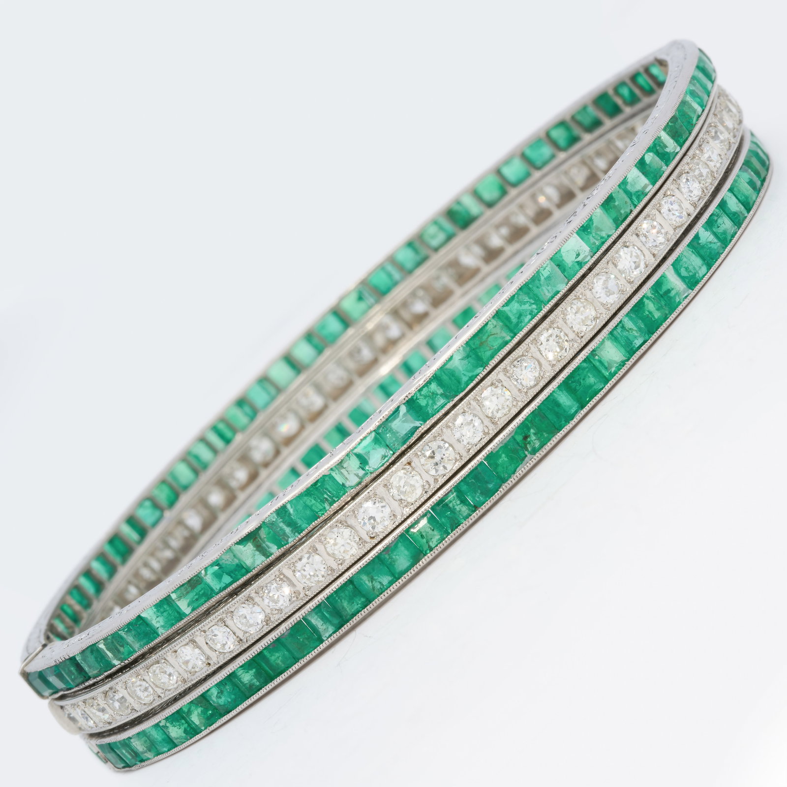EXQUISITE SET OF 3 ART-DECO EMERALD AND DIAMOND HINGED BRACELETS: EXQUISITE SET OF 3 ART-DECO EMERALD AND DIAMOND HINGED BRACELETS,50 grams, platinum.2 bangles fully set with emeralds, totalling approx. 11 ct.1 bangle fully set with diamonds, totalling approx. 4.75 