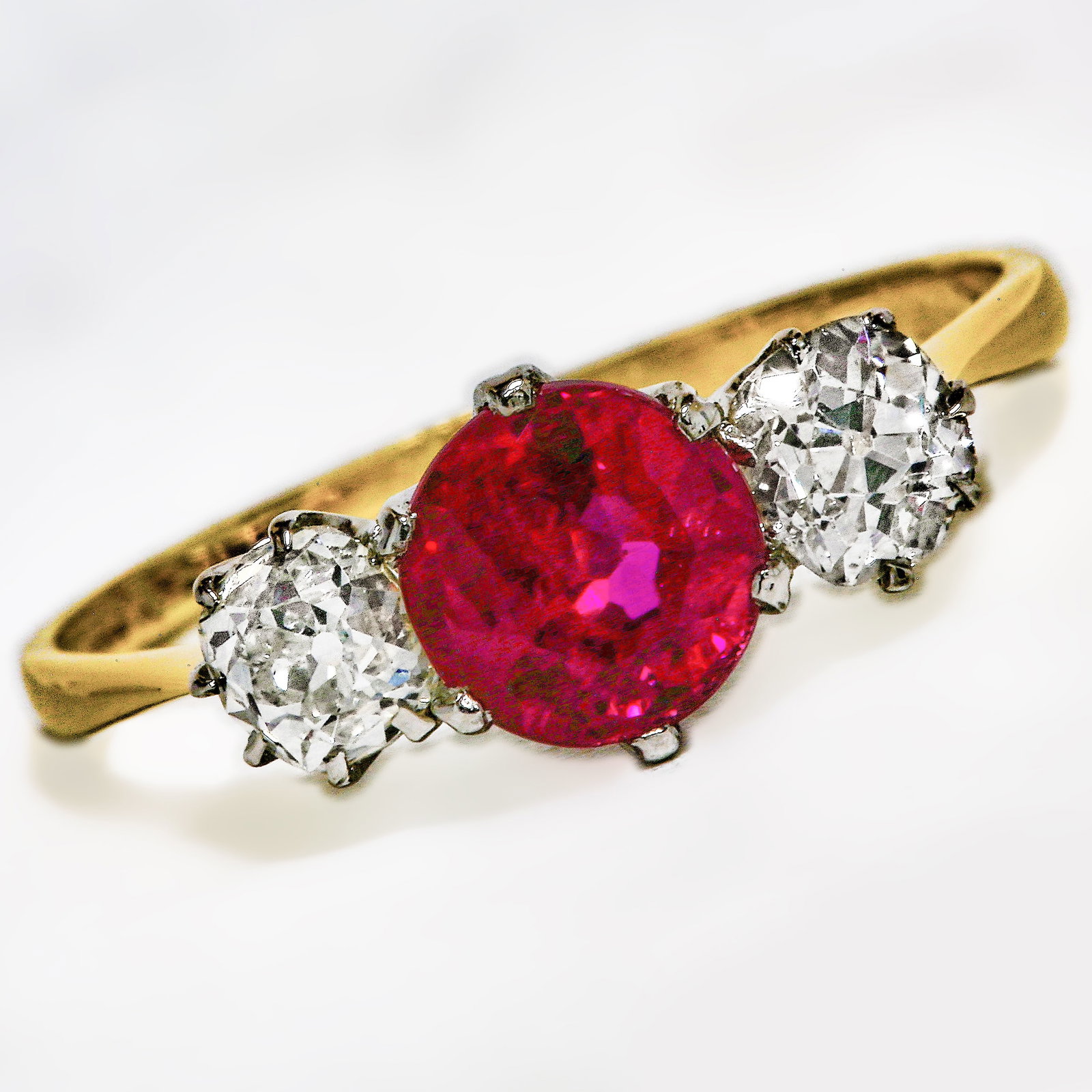 ANTIQUE RUBY AND DIAMOND THREE STONE RING: ANTIQUE RUBY AND DIAMOND THREE STONE RINGStamped 18ct gold.Central ruby of good colour without abrasions. Bright and lively old cut diamonds. Size O.