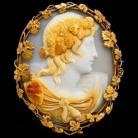 VICTORIAN CAMEO BROOCH: VICTORIAN CAMEO BROOCH,20.1 grams. Testing high carat gold.The fine carved cameo depicting a bacchante.The surmount with fine gold work with relief vine leaves.L. 5.5 cm.