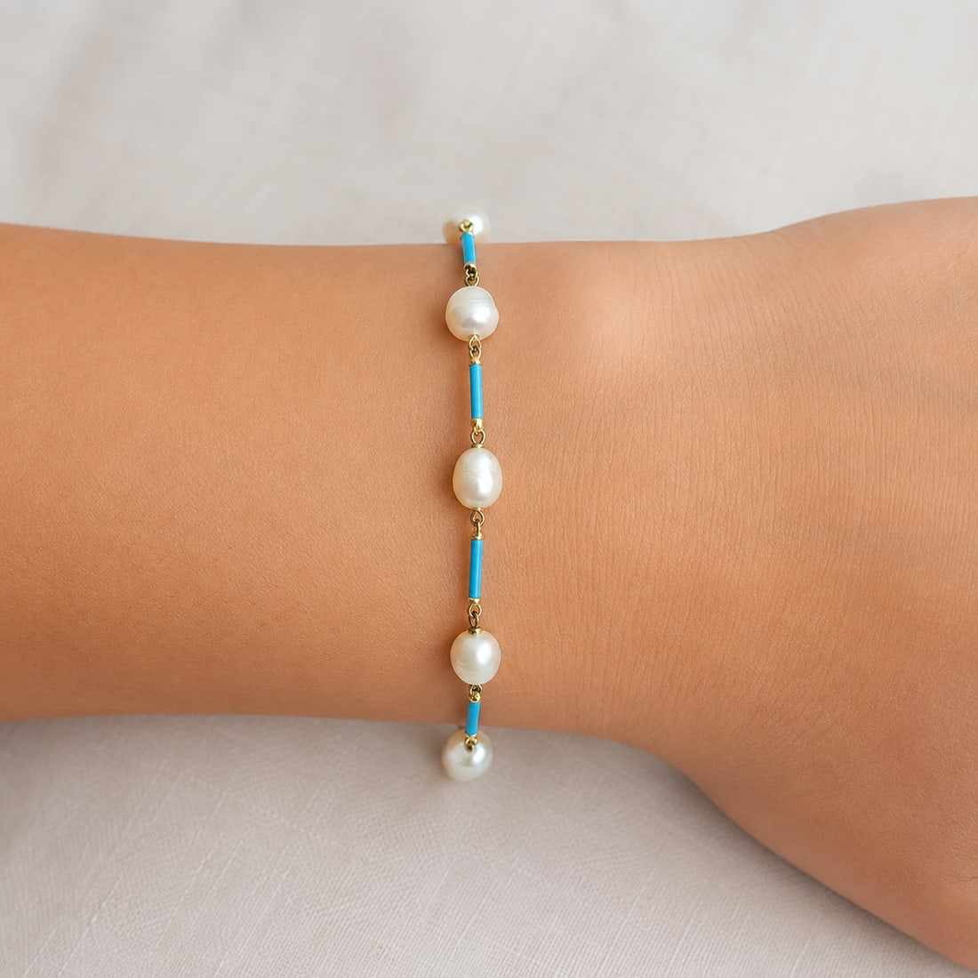 NATURAL PEARL AND ENAMEL BRACELET: NATURAL PEARL AND ENAMEL BRACELET,3 grams, testing 18 ct. gold.Largest pearl of approx. 6.4 mm. Lovely turquoise blue enamel links.L. 18 cm.