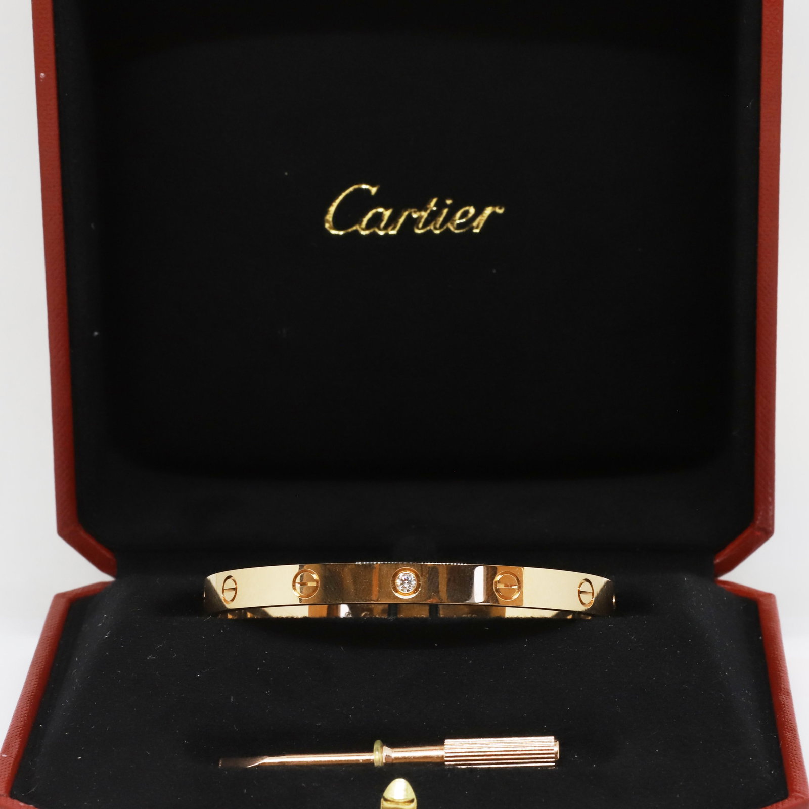 CARTIER DIAMOND LOVE BANGLE: CARTIER DIAMOND LOVE BANGLE,33.9 grams, 18 ct. gold.Rare and unusual Cartier single diamond set love bangle,Diam. 6 mm.Bright and lively diamond.Signed Cartier, Numbered and Cartier makers mark.Size