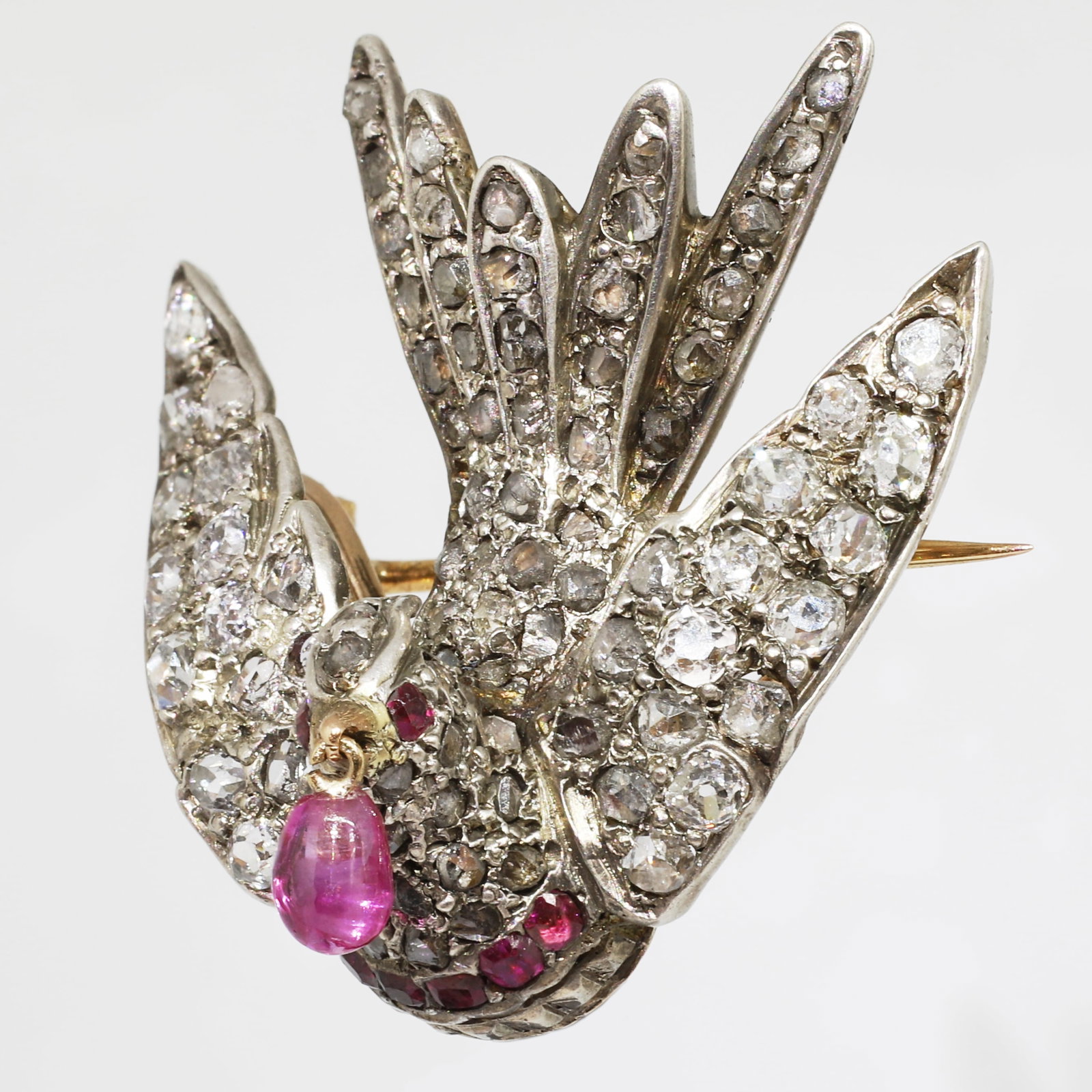 FINE VICTORIAN DIAMOND AND RUBY BIRD BROOCH: FINE VICTORIAN DIAMOND AND RUBY BIRD BROOCH,10.3 grams.Bright and lively diamonds, totalling approx. 2.20 ct.The bird of fine 3 dimensional design.Suspending a ruby drop from it's beak.W. 2.7 cm.