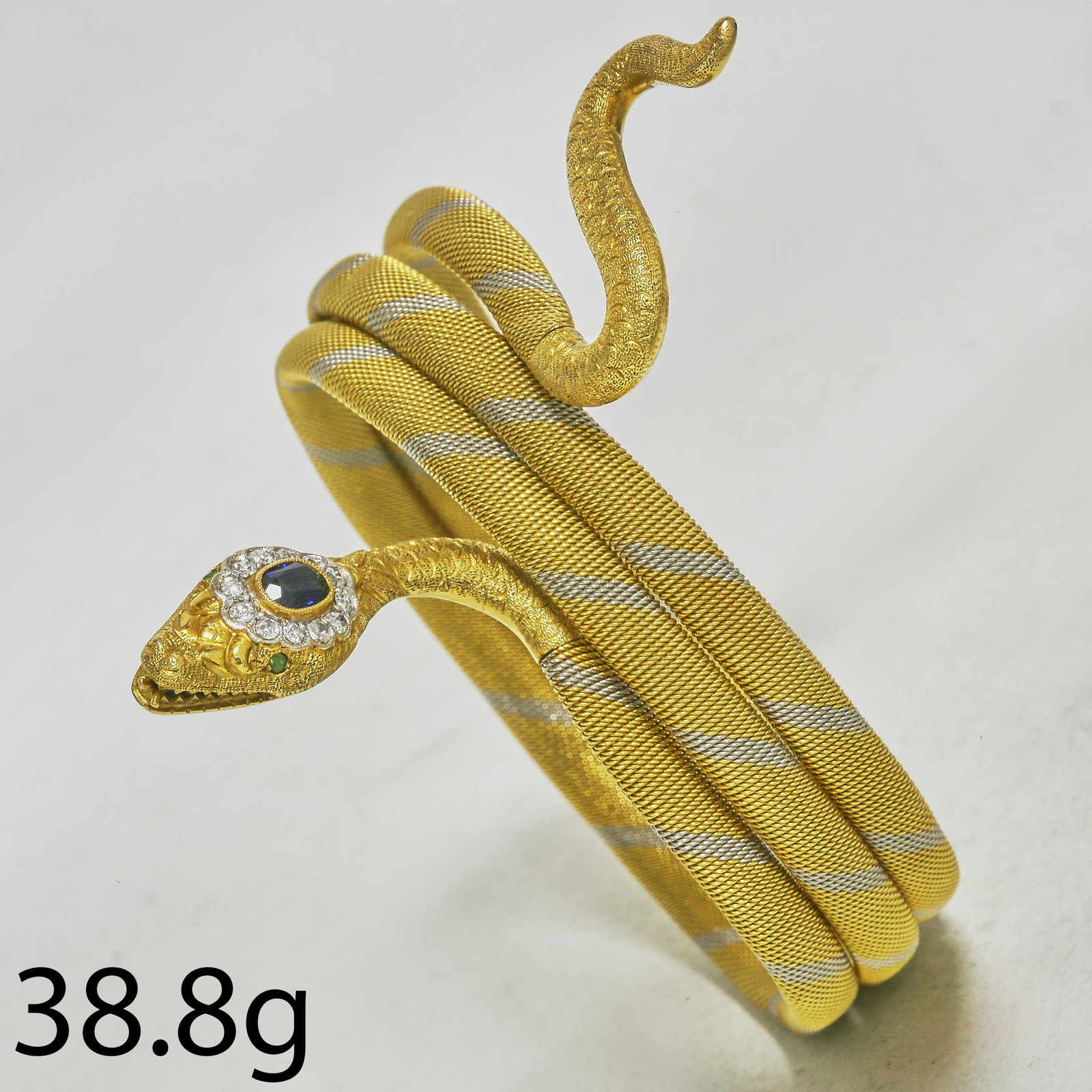 FINE SAPPHIRE AND DIAMOND 2 COLOUR GOLD SNAKE BRACELET: FINE SAPPHIRE AND DIAMOND 2 COLOUR GOLD SNAKE BRACELET,38.8 grams, 18 ct. gold.The head of the snake set with a vibrant sapphire.Diamonds bright and lively.The bangle of 3-coil design.