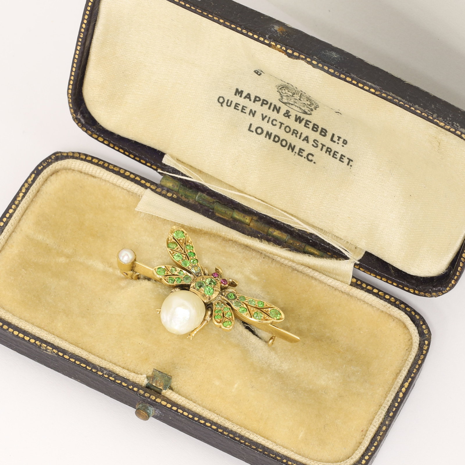 UNUSUAL DEMANTOID GARNET AND NATURAL PEARL BUG BROOCH: UNUSUAL DEMANTOID GARNET AND NATURAL PEARL BUG BROOCH,4.8 grams, testing 15 ct. gold.Vibrant demantoid garnets.The body set with a large natural Salt water pearl of approx. 7.98 x 7.33 x 6.57 mm.W.