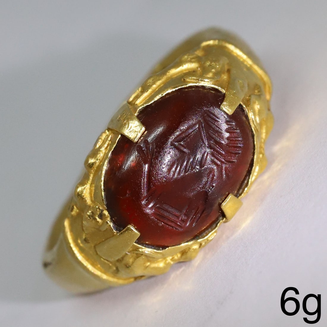ANCIENT PERSIAN GOLD INTAGLIO RING: ANCIENT PERSIAN GOLD INTAGLIO RING,6 grams, testing high carat gold.Set with a fine carved garnet intaglio depicting a man.The sides of the ring head decorated in relief with 4 animals.Size P.