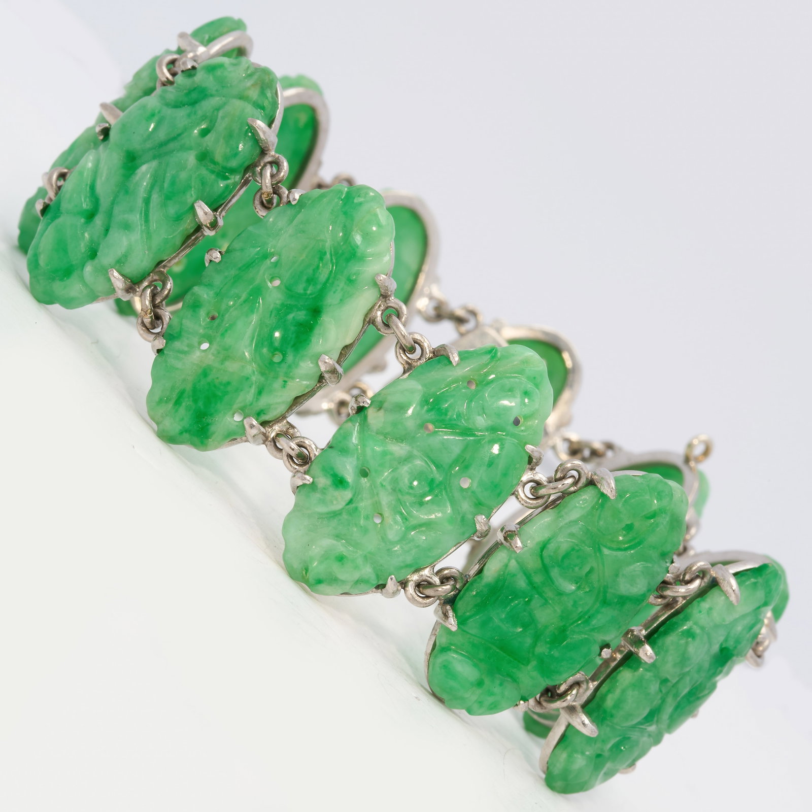 ANTIQUE JADE PANEL BRACELET: ANTIQUE JADE PANEL BRACELET,36.5 grams. 18 ct. gold.11 carved graan jade plauqes, with floral carving.L. 17.5 cm.