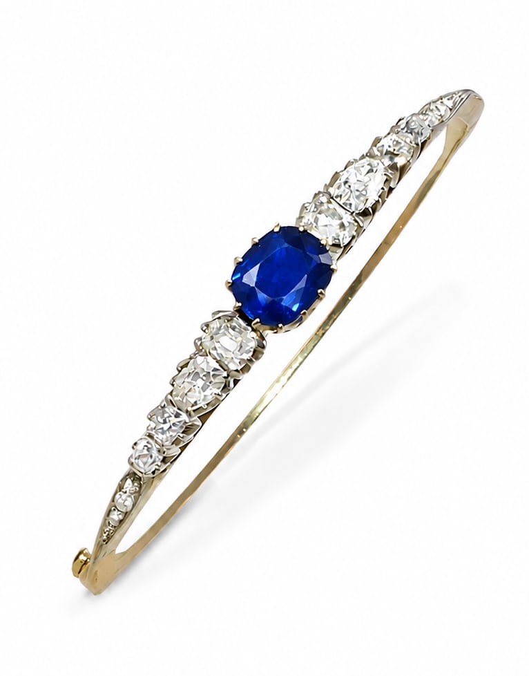 SAPPHIRE AND DIAMOND HINGED BANGLE: SAPPHIRE AND DIAMOND HINGED BANGLE,12.8 grams, testing 18 ct. gold.Rich and vibrant sapphire of approx. 2.12 ct.Bright and lively old cut diamonds, totalling approx. 1.70 ct.Inner diam. 5.8 cm.