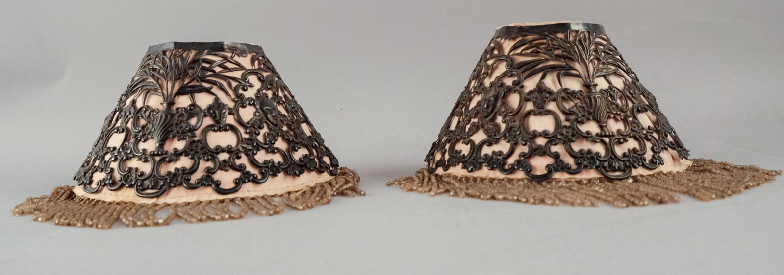 Pair of Tiffany Sterling Silver Lampshades: Tiffany, 19th century, having glass bead fringe and mica interior, decorated with neoclassical masks and urns surrounded by flowers. Hallmarked as shown. Height of shade not including fringe: 3 1/4" D