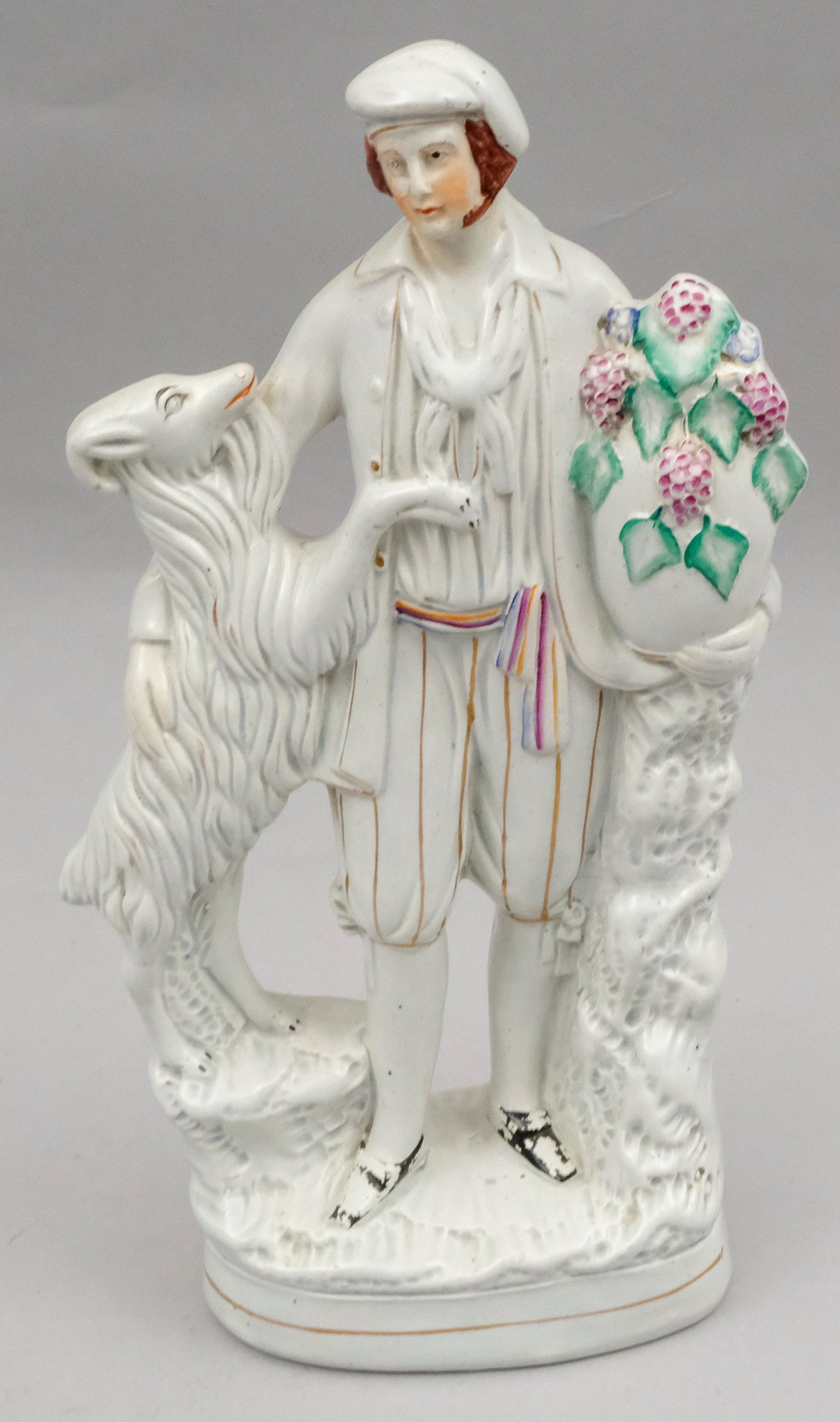 Large Staffordshire Figurine of a Goat Herder: With white goat and urn of grapes. Chapeued in a jaunty cap. 14 1/2".