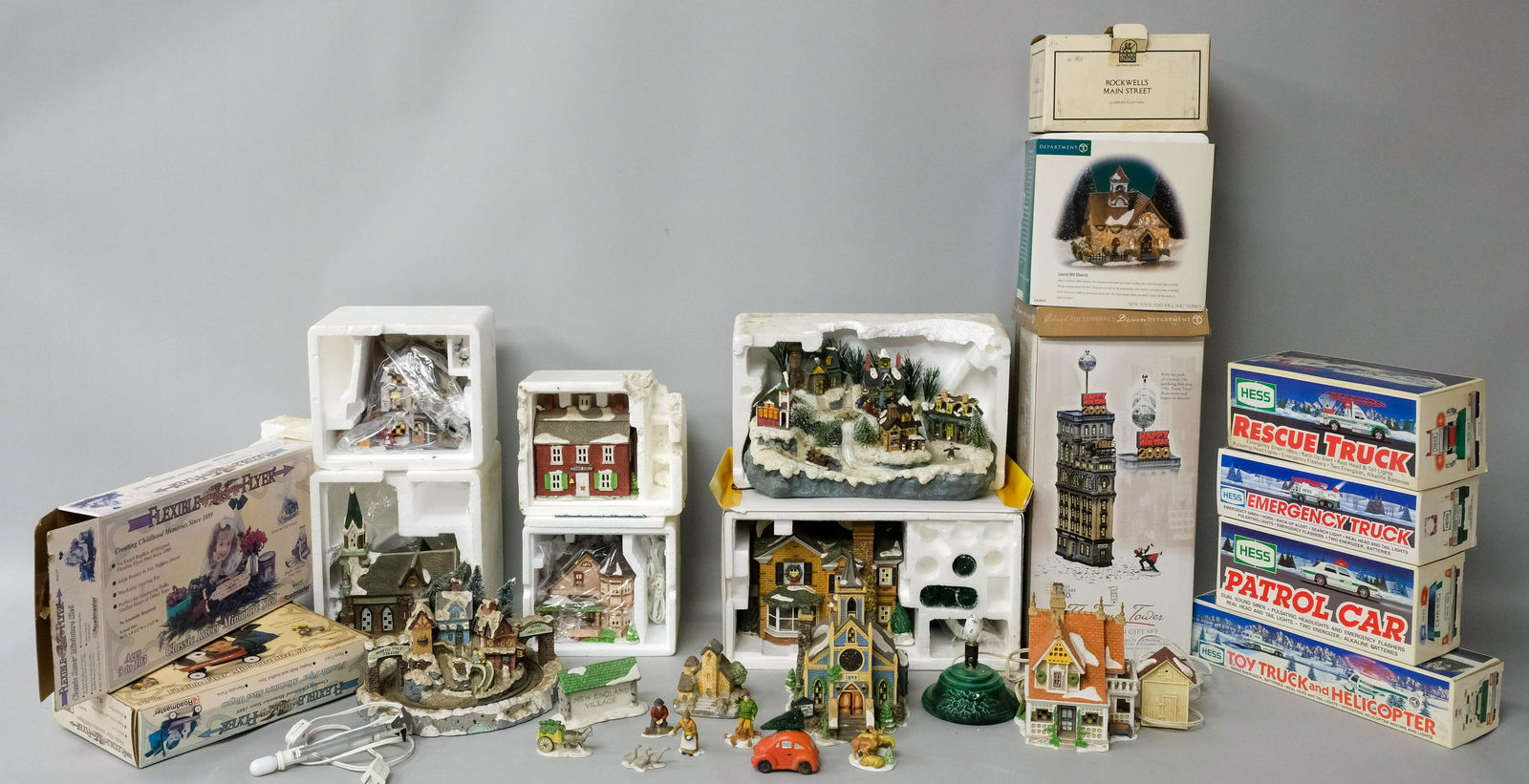 Large Lot of Collectibles, Hess, Dept 56, Avon: Comprising a boxed Hess Toy Truck, Helicopter, Patrol Car, Rescue Truck, Emergency Truck, Flexible Flyers, Avon Christmas Optic Village, Dept 56 Holly Lane and Town Hall, together with empty boxes and