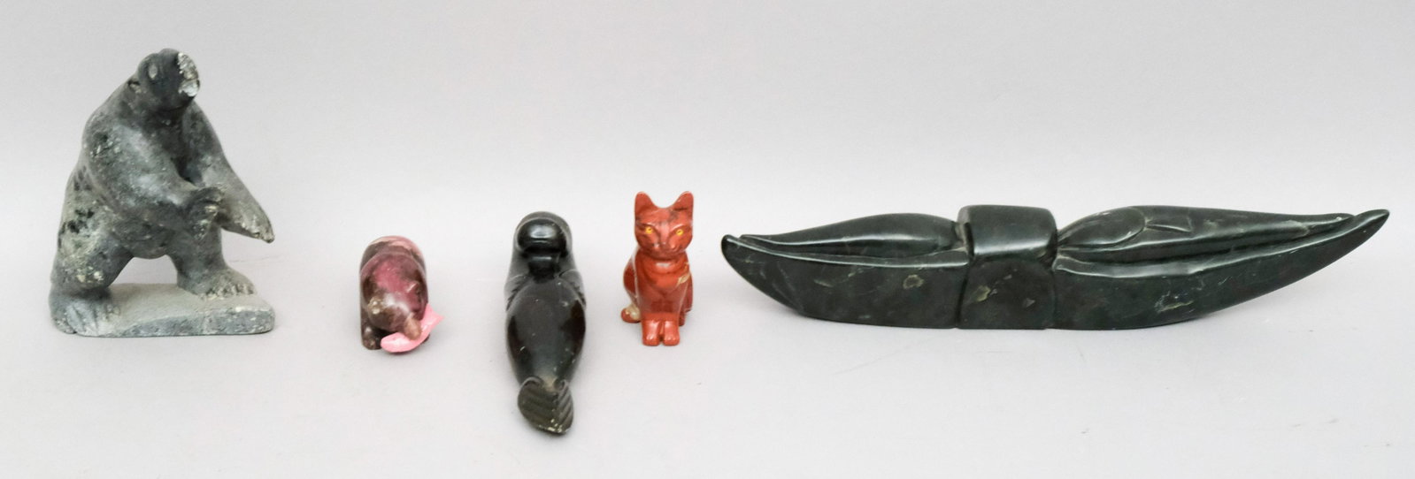 Group of Inuit or Eskimo Stone Art Carvings: 3 Pieces of Canadian Inuit art, signed and with paper labels, comprising a canoe, bear, and seal. Together with 2 stone carvings possibly Russian, of a seated cat and bear holding a salmon. 2 1/2" to 