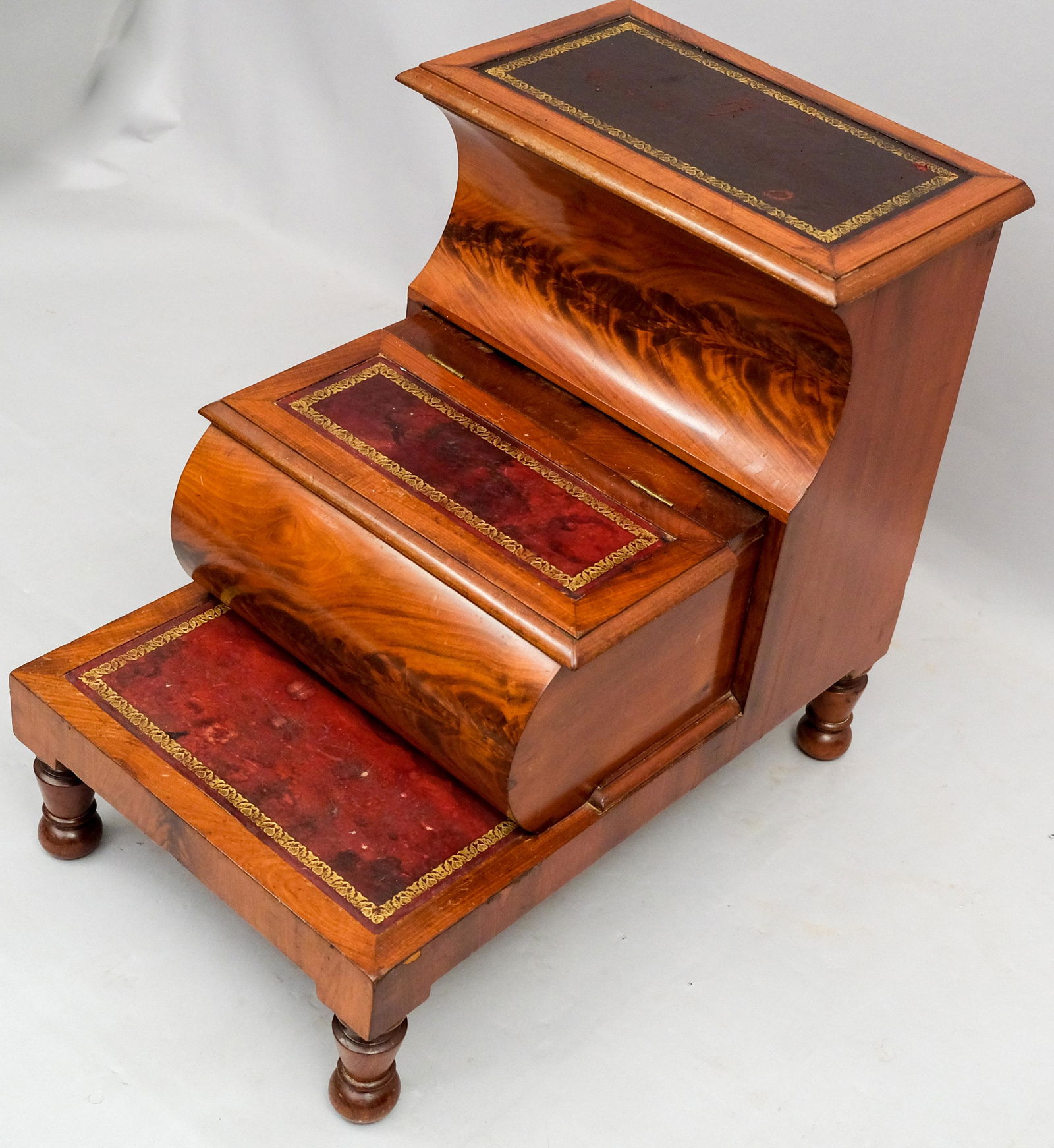 English Victorian Flame Mahogany Library Steps: With red tooled leather and the top and middle step doubling as storage chest. 19" x 27 1/2" x 25 1/2".