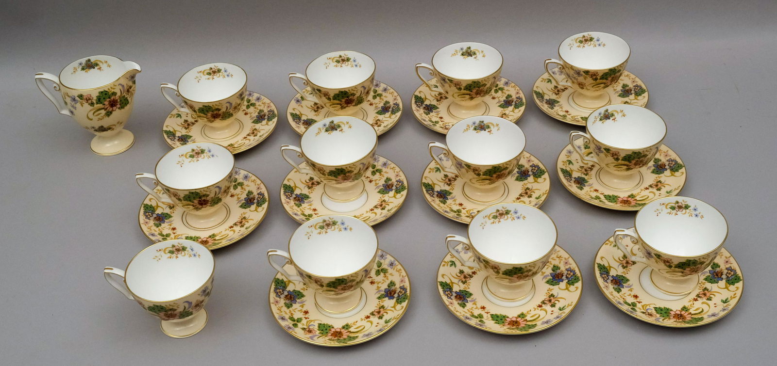 Lot of Royal Worcester Tea Cups.: Comprising 12 teacups, 11 saucers, and a creamer in a light peach field with floral decoration.