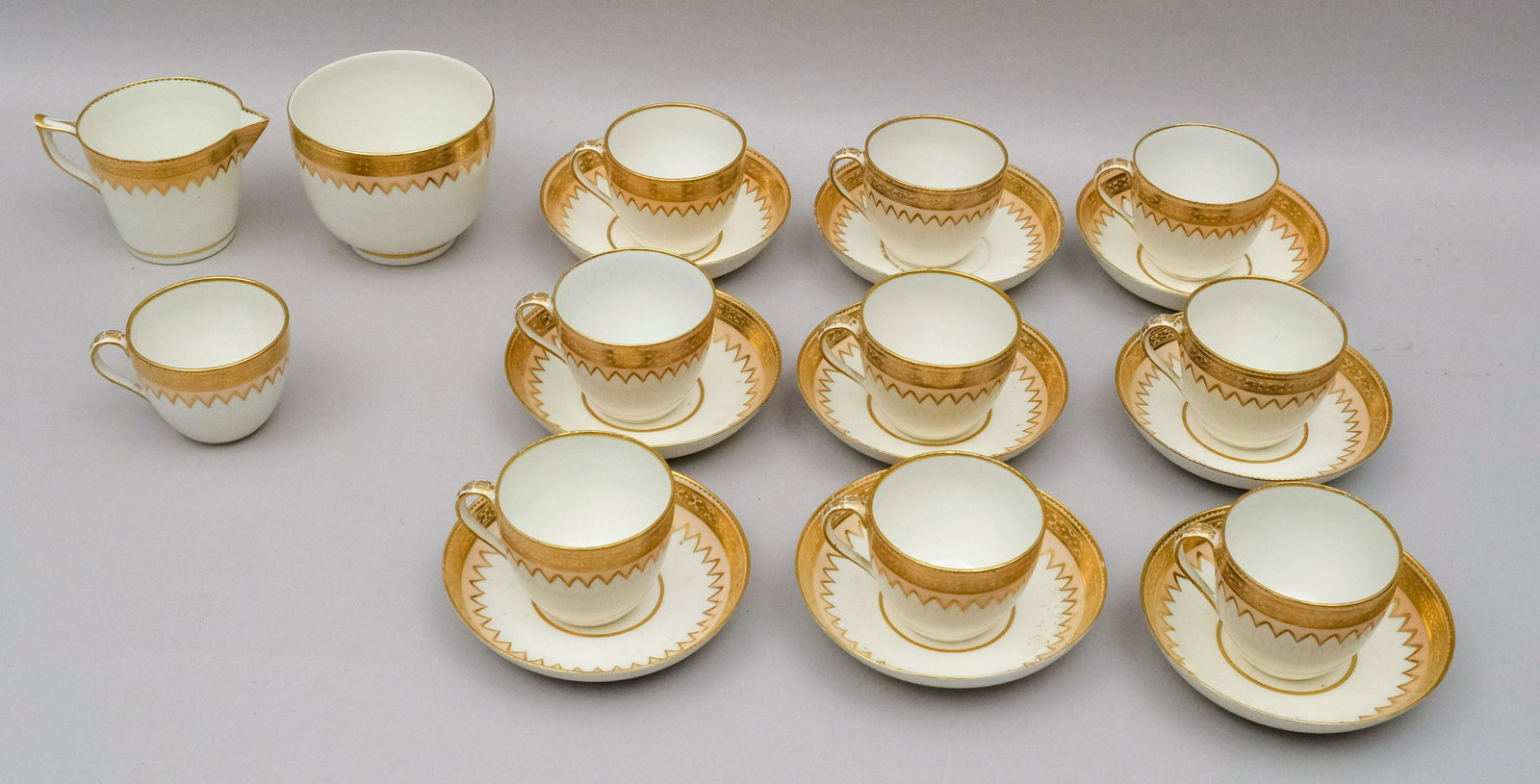 Lot of Early 19th Century Derby Porcelain: Decorated in a pink peach glaze with gilt borders. Comprising 10 cups, 9 saucers, a creamer and open sugar. Marked as shown. Cups measure. 2 1/2" x 3 1/8.