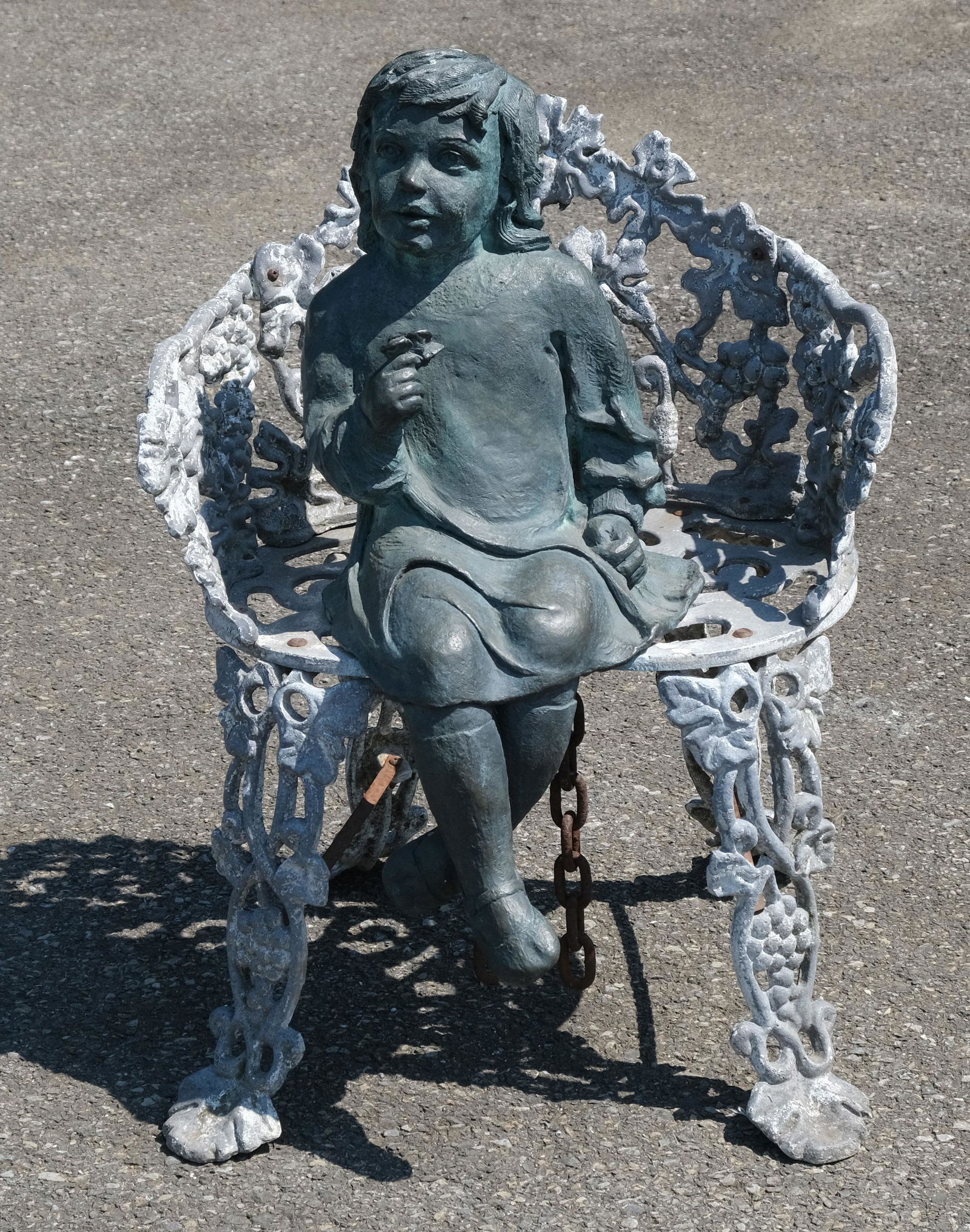 Bronze Sculpture of Garden Girl in Cast Iron Chair: Assembled sculpture of seated young girl in cast iron chair decorated in grapes. 29" tall, 20 1/2" wide, 15" deep.