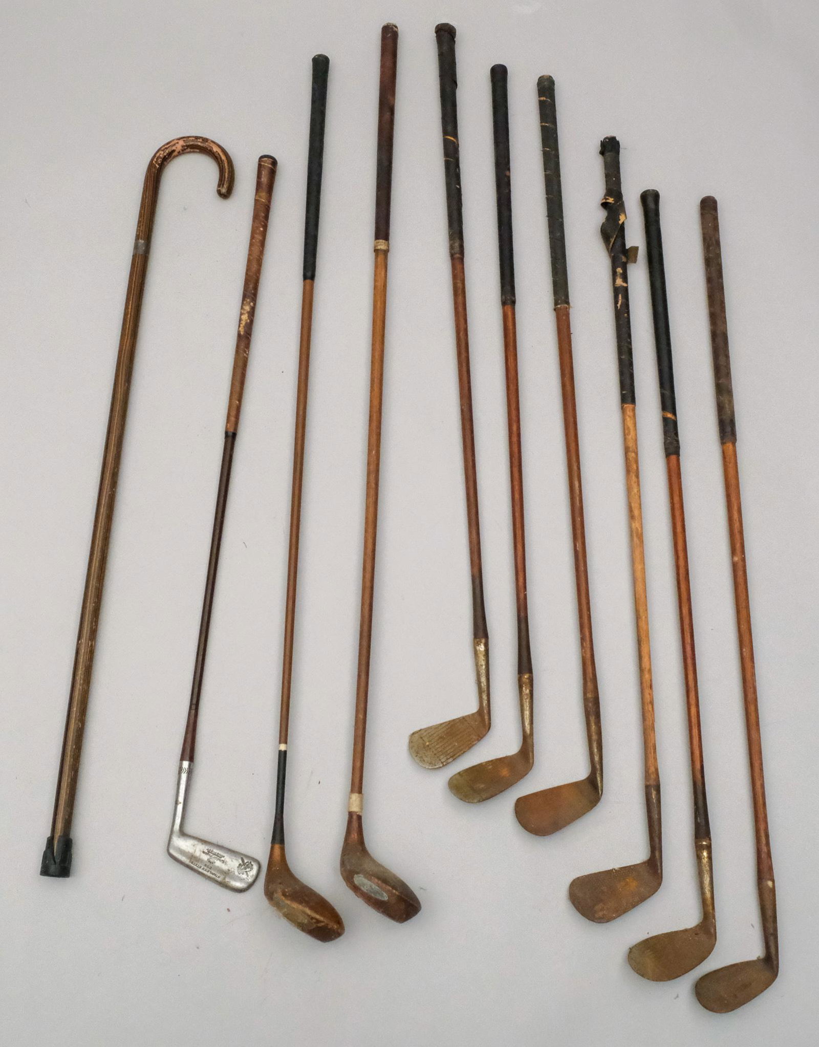 Lot of Antique Wood Shaft Golf Clubs: Including Ditson. Together with a faux macassar cane with sterling silver band.