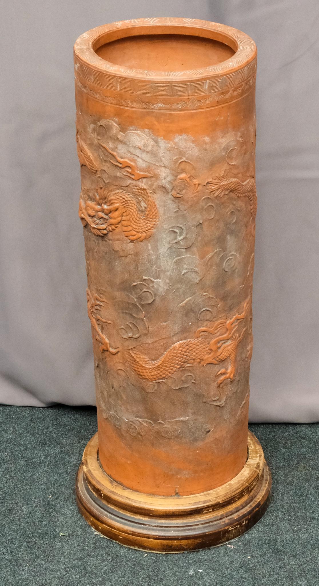 Antique Chinese Terracotta Umbrella Stand: Finely decorated and applied dragons, with stipple and incised cloud and key decorations. Mounted in pillar style wooden base. Measures 26" tall.