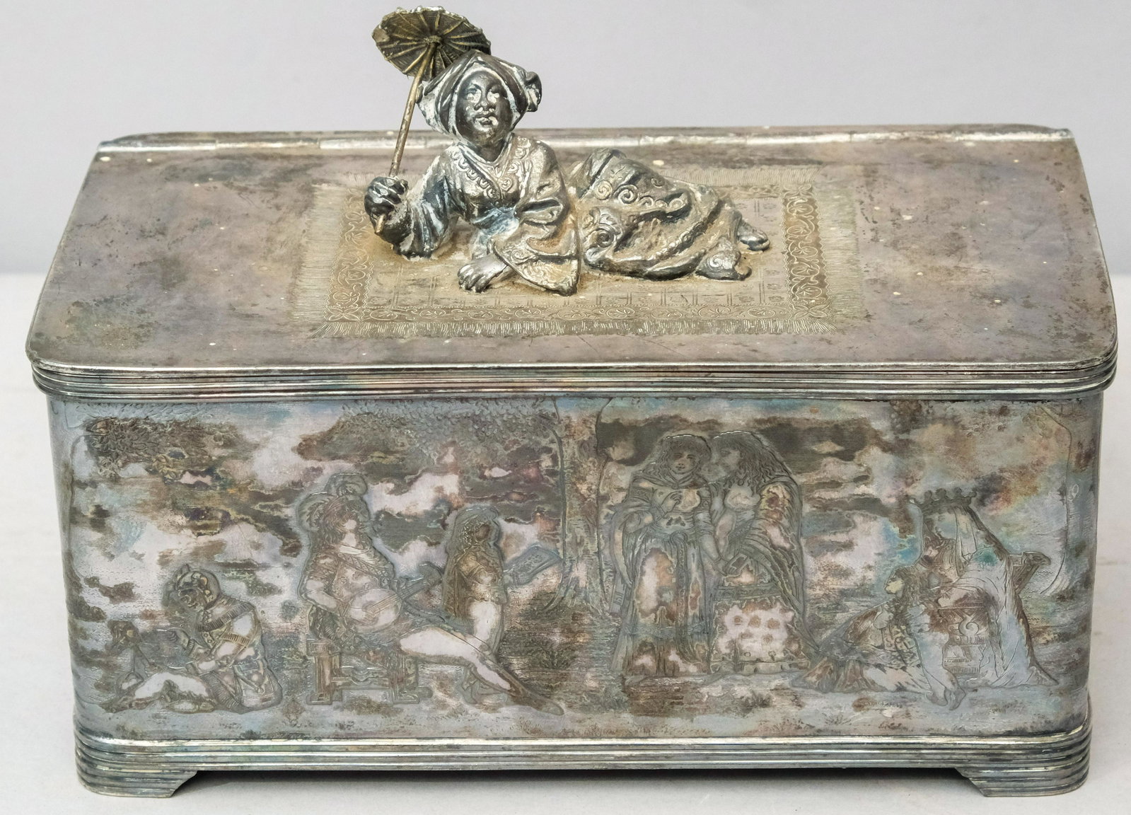 Simpson Hall & Miller Silverplate Humidor: With Orientalist figure holding parasol reclined on rug and engraved courting scenes all around body. Marked as shown. 6 14" x 8 3/4" x 5 1/4". Fun piece of figural silverplate.