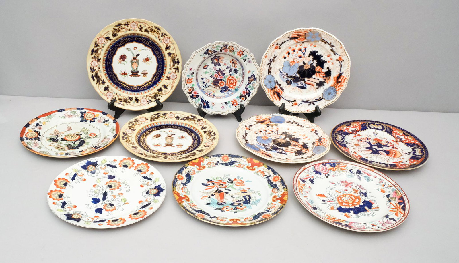 Lot of Ironstone Imari Dinnerware: Various makers. One soup bowl and nine plates. Bowl measures: 8 3/4" diameter. Plates range from 10" in diameter to 10 1/2" in diameter.