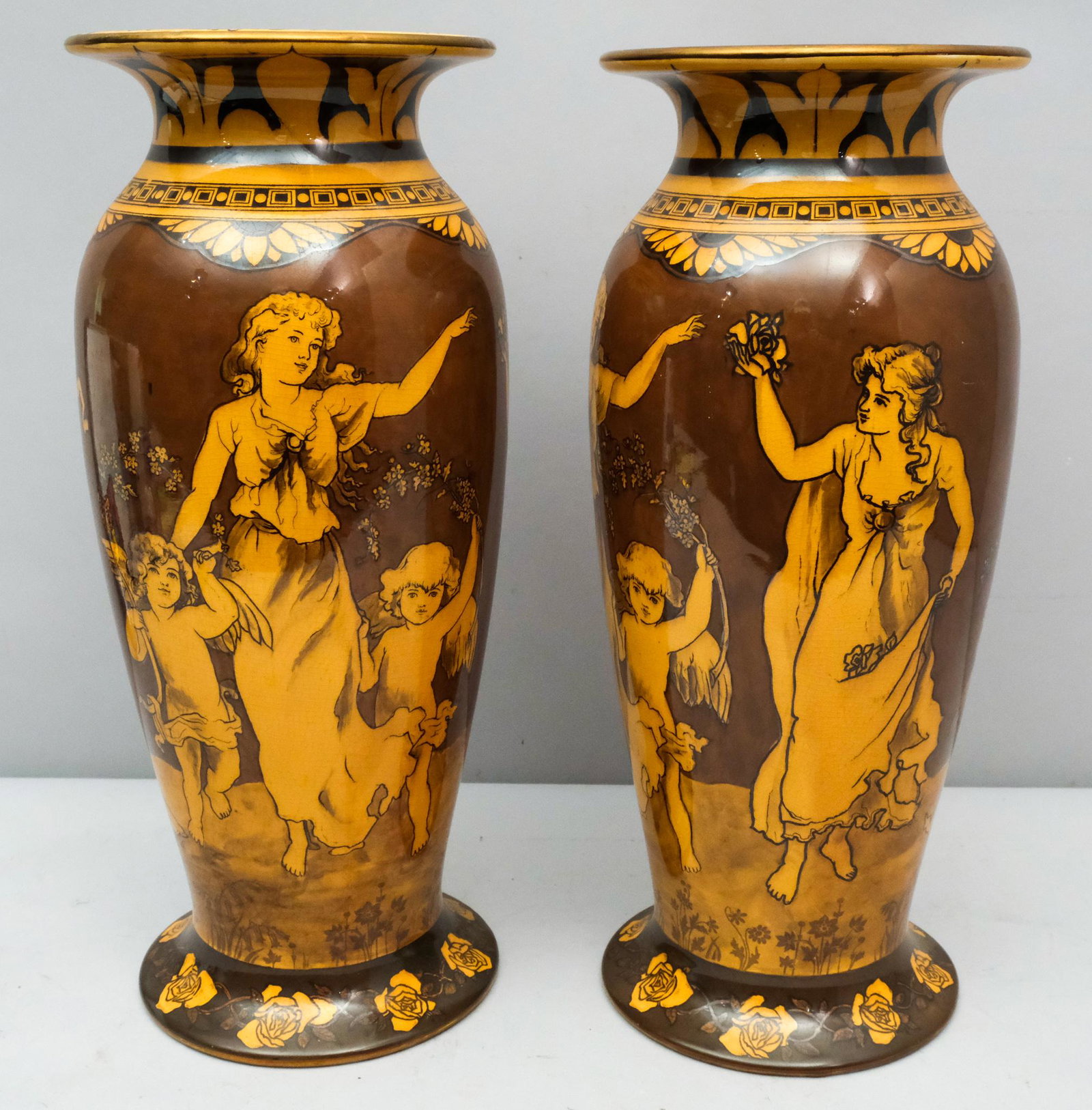 Large Pair of Morrisianware Doulton Vases: Fabulously decorated earthenware vases with neoclassical barefooted maidens frolicking. Measure 7" x 17 1/4" height. Marked as shown.
