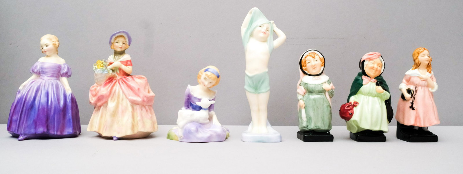 Lot of 7 Royal Doulton Small Figurines: Comprising the following: "Mary had a Little Lamb", "To Bed", "Mrs Bardell", "Little Nell", "Sairey Gamp", "Marie", and "Cissie". Marked as shown. 3 1/2" to 6 1/4".
