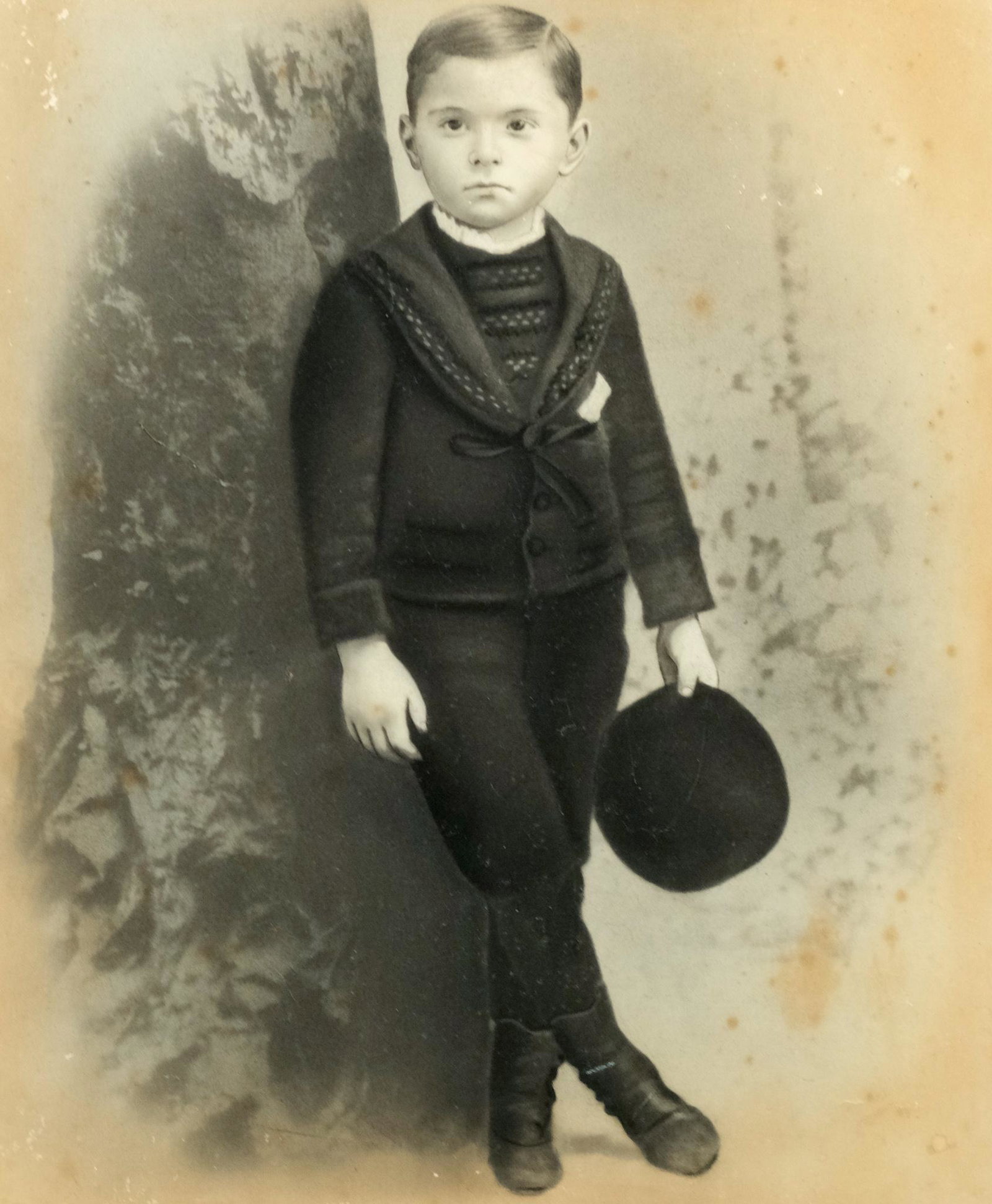 Enhanced Photograph of a Little Boy: Turn-of-the-century enhanced photograph of a little boy all dressed up in a ribbon-tied jacket, knickers and button up boots, holding his hat. 16" x 20"