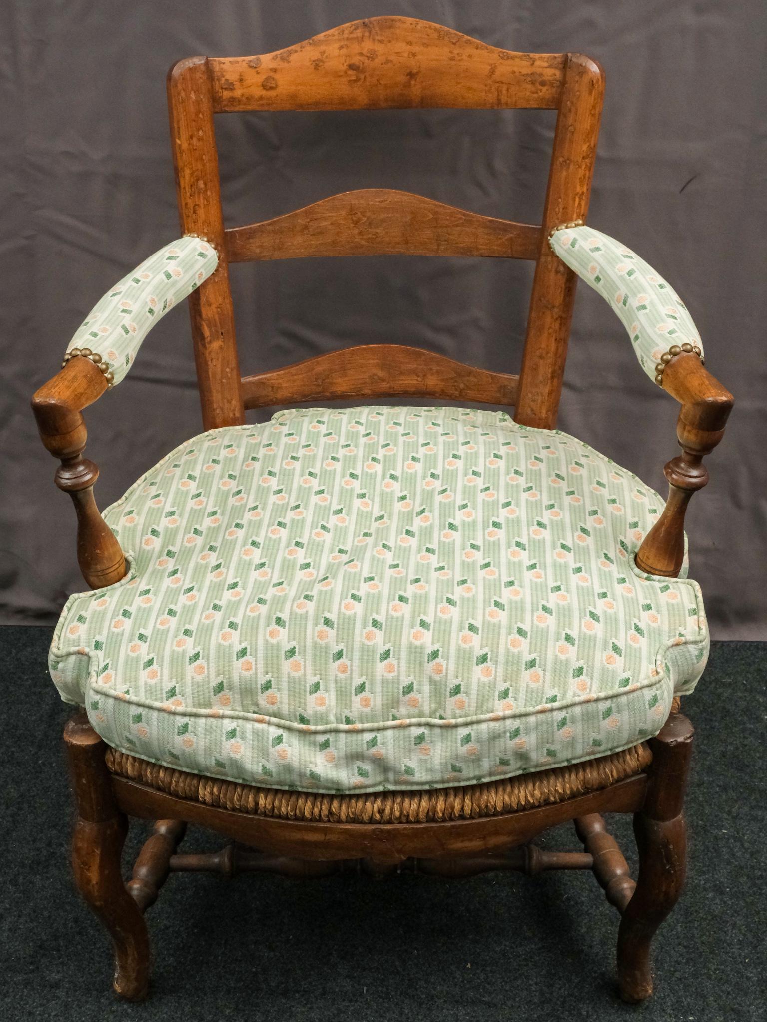Ladderback Reed Seat Upholstered Arm Armchair: 19th century French armchair having a ladderback, reed seat, upholstered arms with brass tack accents and a comfy seat cushion. 25" W X 23" D X 35 3/4" H