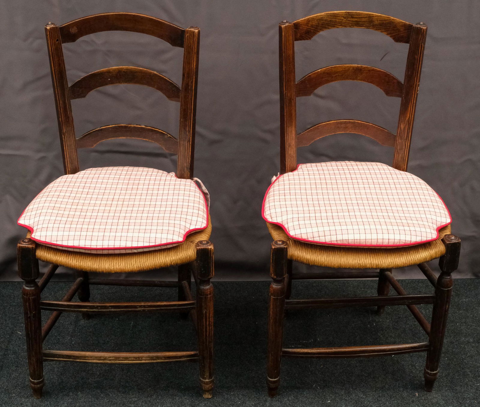 Pair of Arched Ladderback Rush Seat Chairs: Pair of arched ladder back carved rush seat chairs with pink and white striped tie-on cushions. 16 1/4" W X 13 1/2" D X 33" H