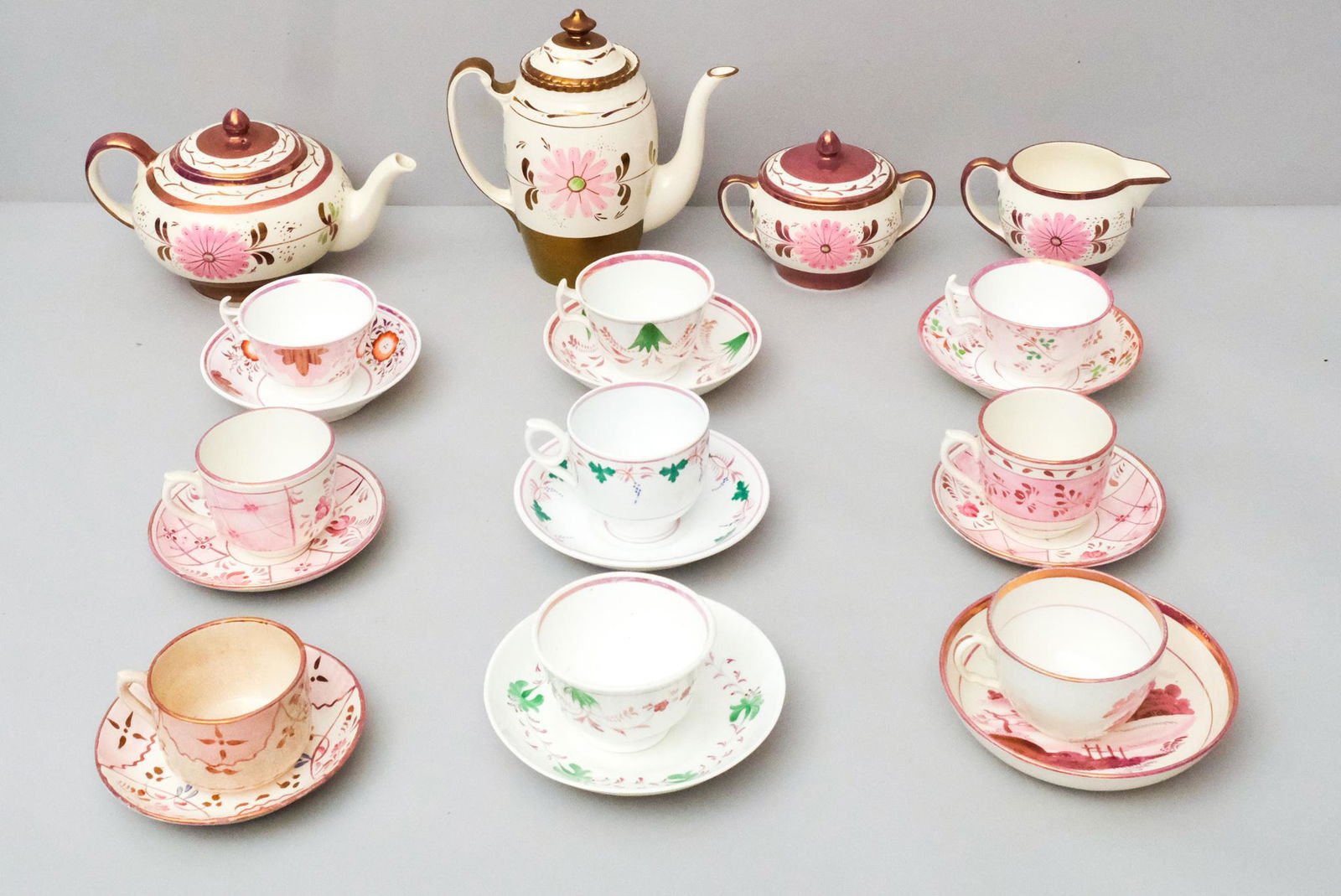 Group of Pink Lustre Tea Pots and Cups: Variously decorated and some with maker's marks. Largest piece, tea pot, 5" high x 9 1/2" wide, smallest piece, tea cup, 2 1/2" x 3 1/2".