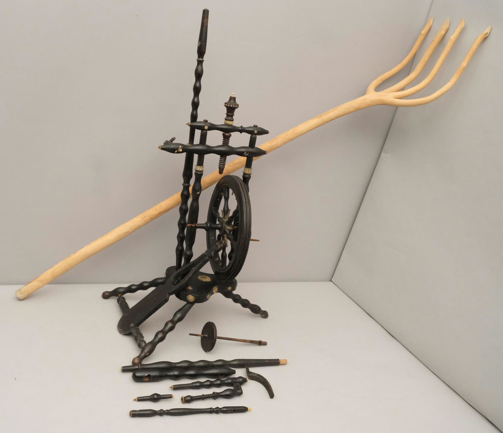 Wooden Carved Pitchfork and Spinning Wheel: The pitchfork hand carved, the wheel of diminutive stature, ebonized with bone inlays and applique. Wheel measures 13 1/2" X 19" X 21", fork measures 9" X 55".