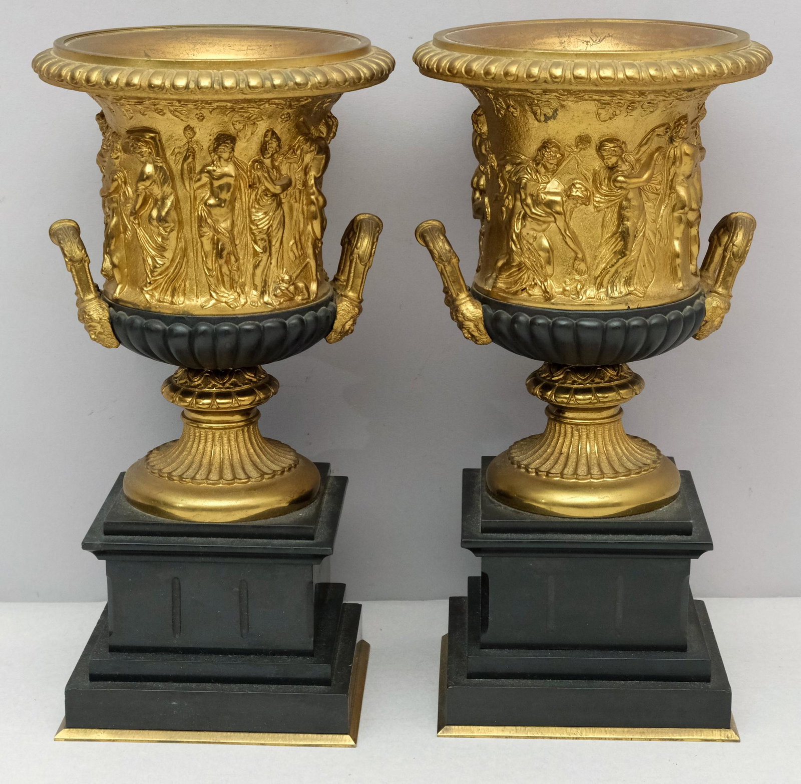 Pair of Neoclassical Gilt Bronze Urns: With high relief figures and black accents. On black onyx bases. Marked as shown. 5 1/2" W x 12" H.