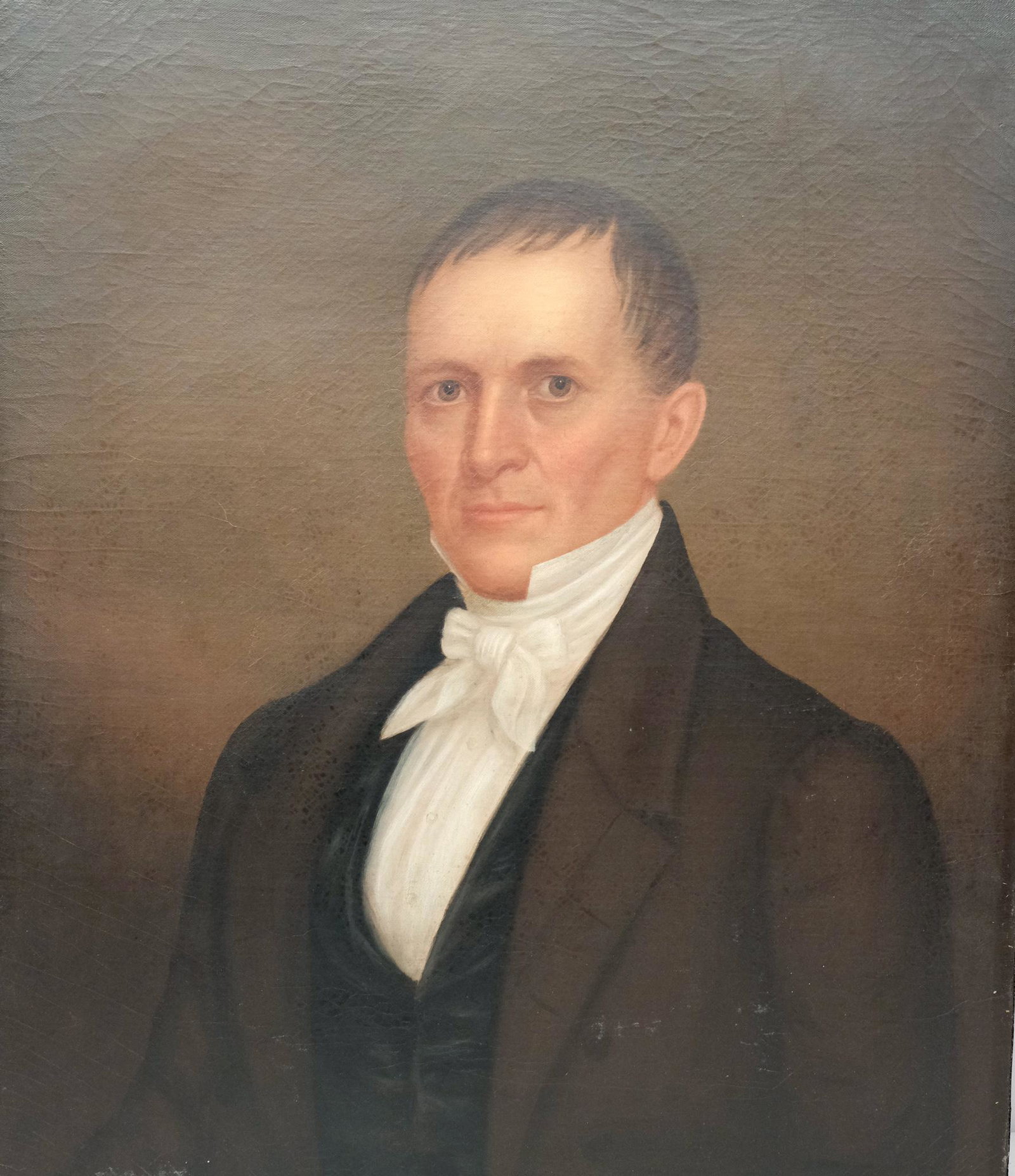 American School, Portrait of a Gentleman: American, 19th century oil on canvas portrait of a gentleman in a dark brown waistcoat and a slight smile, 25" x 30 1/2" overall.