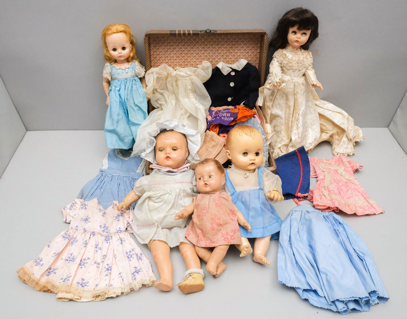 Dolls & Accessories, Madame Alexander, Effanbee: Lot consisting of an early twentieth century doll carrying case from Worcester T&S (5" H x 12" W x 9" L) filled with handmade dolls' clothes; a 1900 German bisque baby doll with brown eyes and curly h