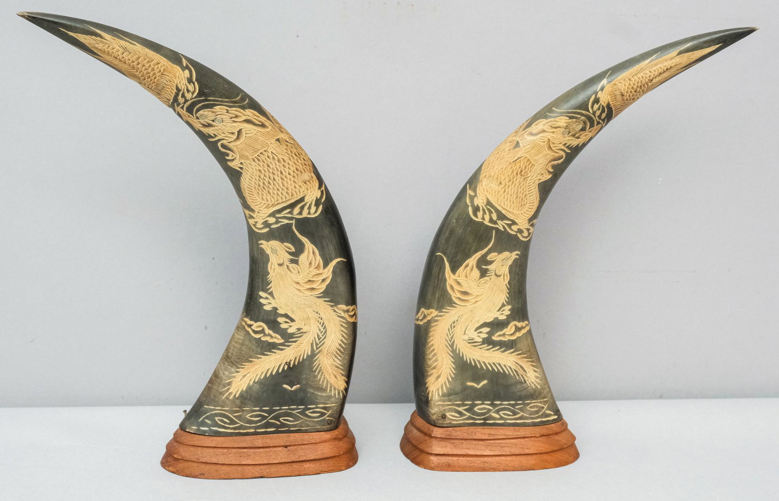 Pair Chinese Carved Phoenix & Dragon Ox Horns: Mirror carved with deep and intricate detail, mounted on wooden plinths. 13 1/2" tall.