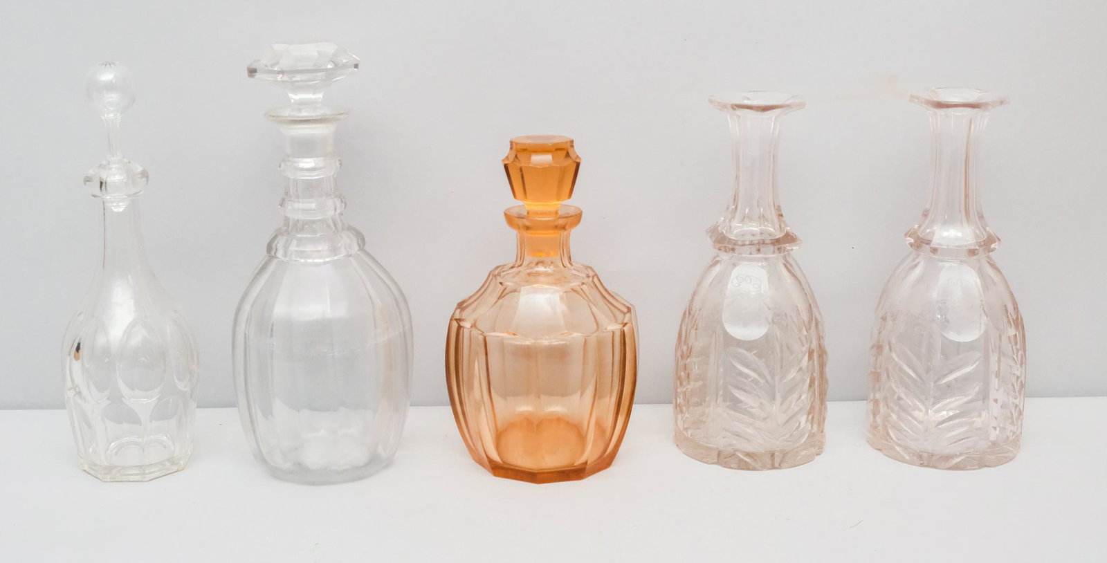Lot of Mixed Vintage Decanters: Lot consisting of a pair of clear faceted glass decanters with frosted leaves and vines motif (10" H); a vintage cut rose red whiskey decanter with topper (9 1/4" H); a clear, rounded glass decanter w