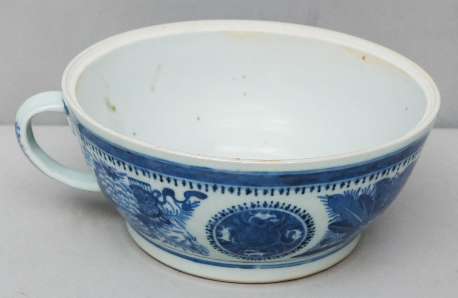 Large Blue & White China Bowl with Handle: Large, early 20th century blue and white china bowl with a handle, 4" H x 10 1/2" W x 9 1/4" L. Possibly a store display for a teacup.