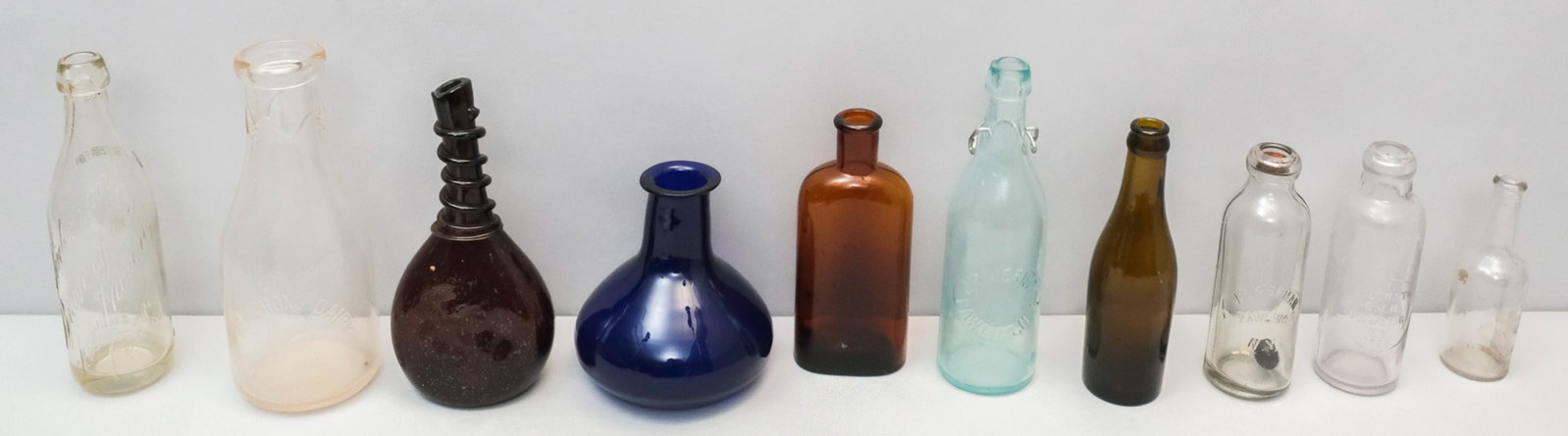 (10) Vintage Glass Bottles: Lot of 10 vintage glass bottles. Labeled bottles include J.P. Kiernan Pawling NY, Heinchon's Dairy Pawling NY, and Weidemann Brewery New Haven CT. Largest measures 3 3/4" X 9 1/2".