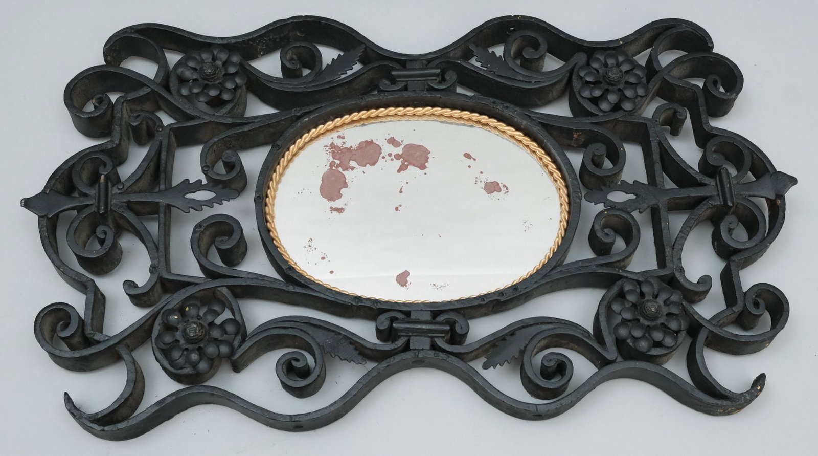Scrolled Wrought Iron Mirror: Late 19th century scrolled wrought iron mirror with gold braided edging, 22 1/2" x 13" overall.