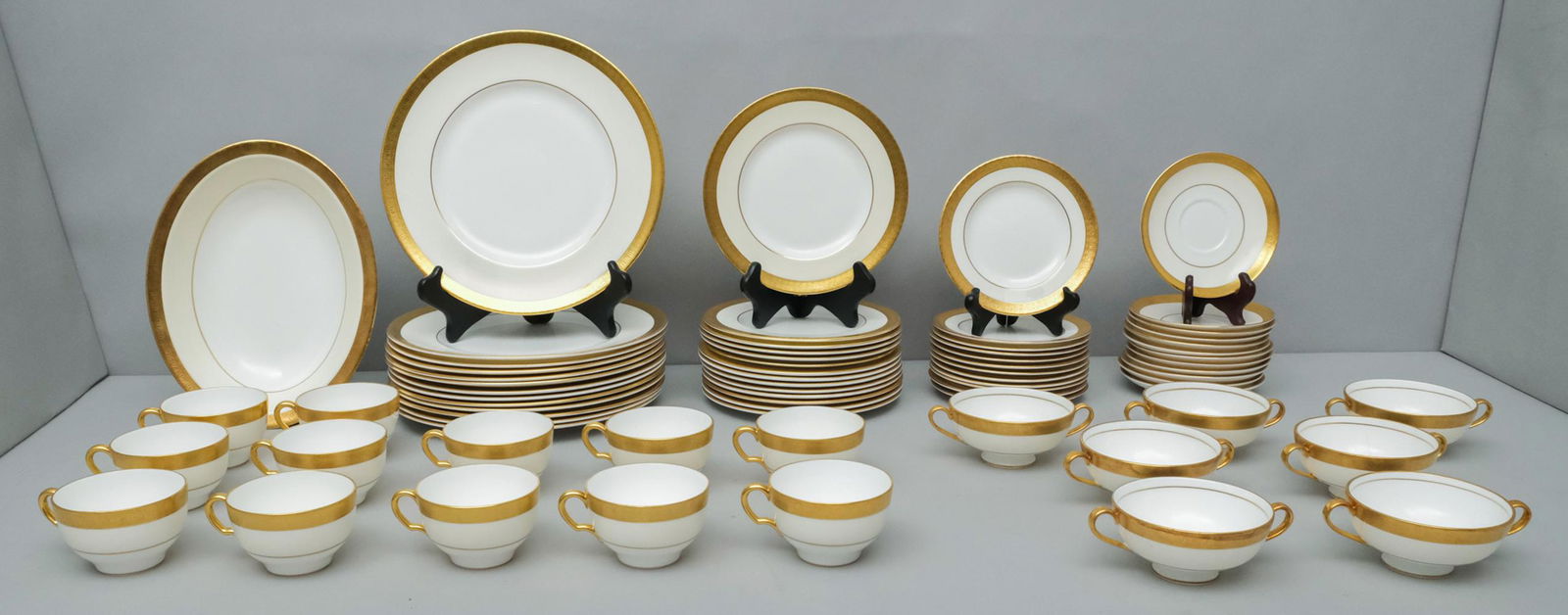 Lot of Minton Buckingham K159 Pattern Bone China: Large lot of Minton Buckingham pattern bone china with Gold encrusted edges, cream rim and white centers, marked on bottom. Lot includes 10 3/4" oval serving dish, fourteen 10 1/2" dinner plates, four