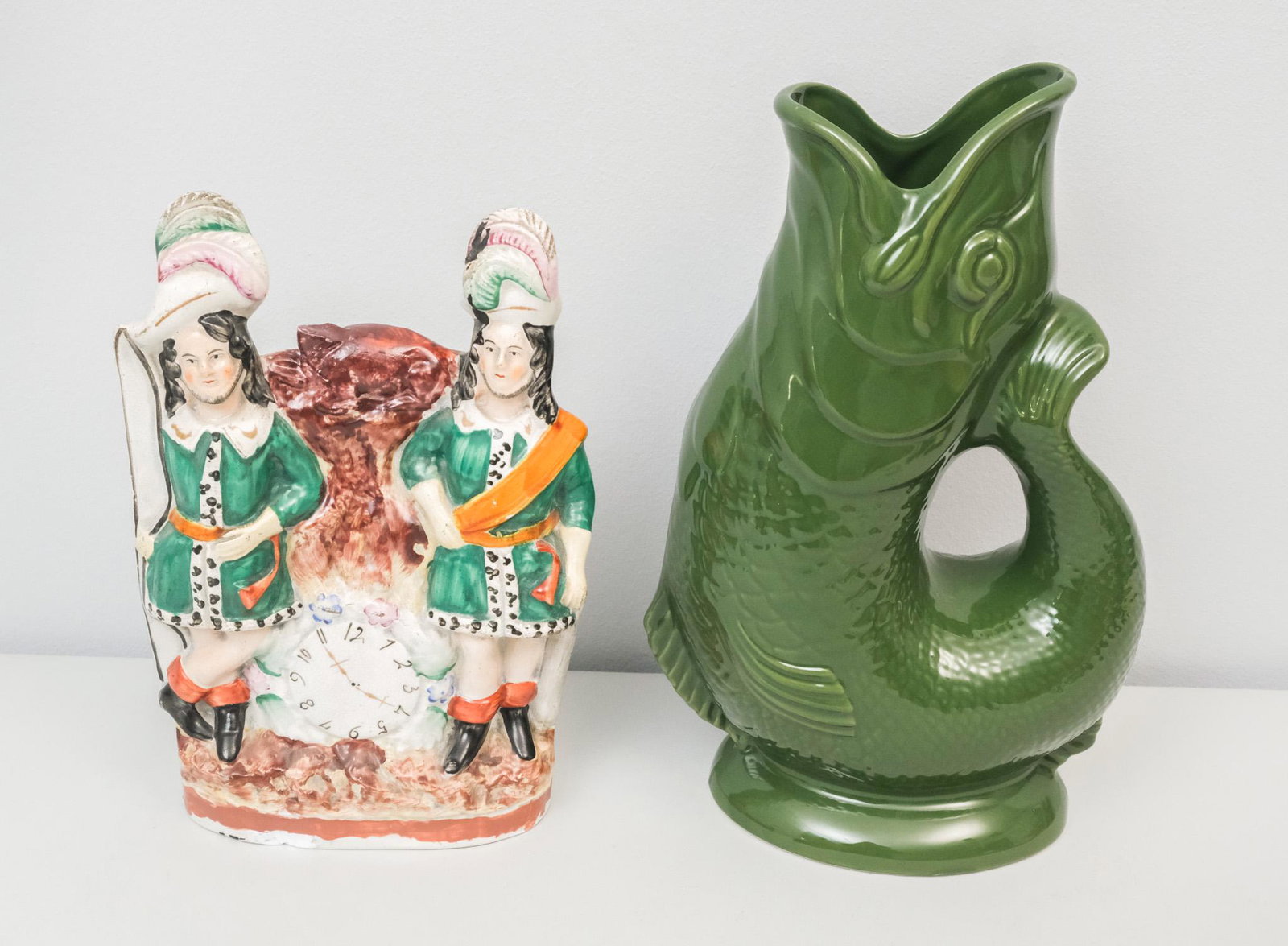 Antique Staffordshire Pottery Figure & Pitcher: Lot consisting of 1) English, 19th century Staffordshire hunting figure, with two hunters flanking a painted clock, 9" H x 6 1/4" W x 2" L; and 2) English, Wade ceramics Gluggle Jug in the form of a f